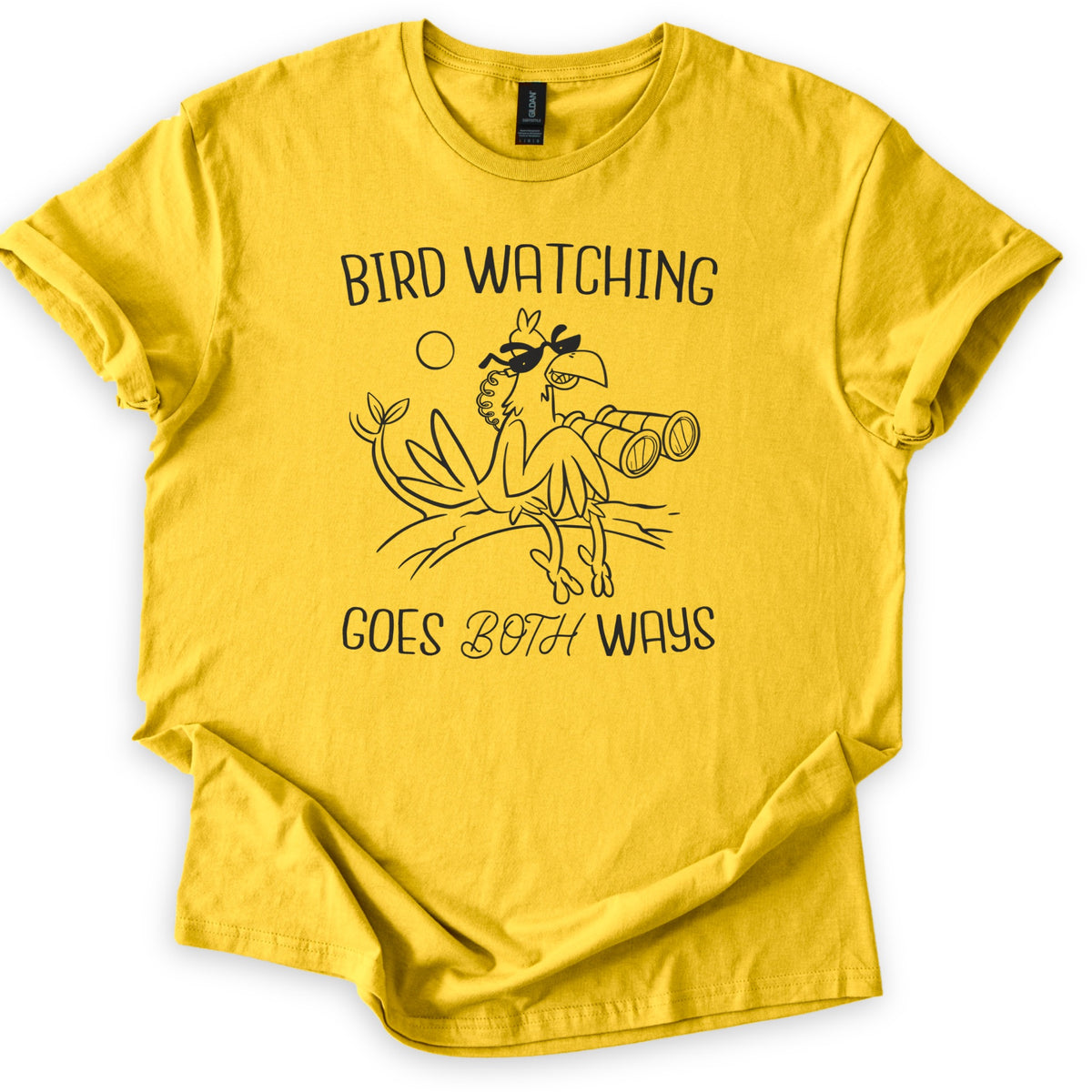 Birds Watch Back Birder Comfort Colors T-shirt in Daisy, laid flat. Black line art of a cartoon bird in sunglasses perched on a branch beside a pair of binoculars, with a small sun, between the words Bird Watching Goes Both Ways. Sleeves rolled, on a white background.