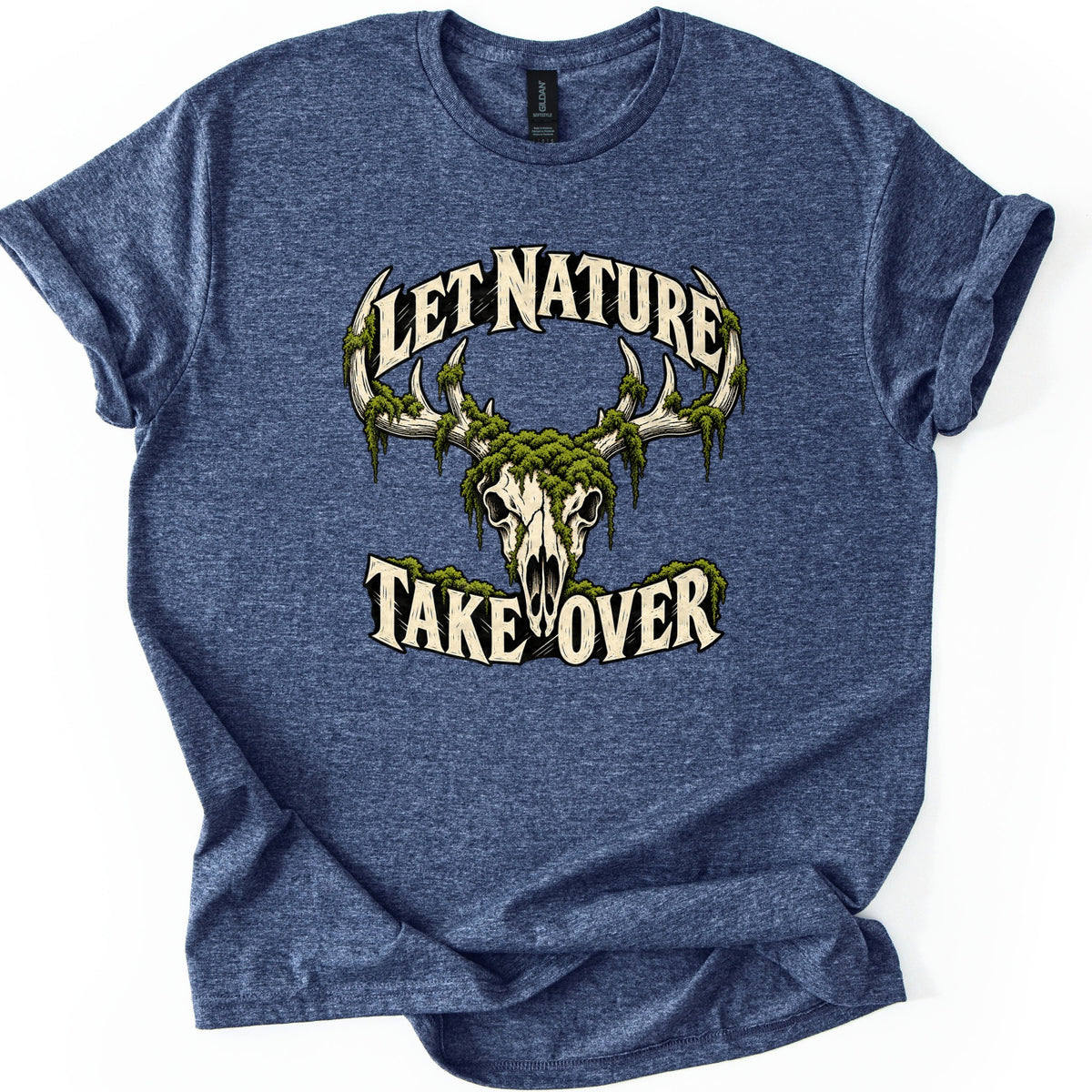Let Nature Take Over Comfort Colors T-shirt in Heather Navy, laid flat. A cream deer skull with antlers draped in green moss sits between the words Let Nature arched above and Take Over below, in cream lettering. The sleeves are rolled on a plain white background.