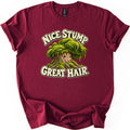 Nice Stump Great Hair Comfort Colors T-shirt in Maroon, laid flat. A smiling cartoon tree stump with a thick mop of green moss like hair, between the words Nice Stump and Great Hair. in cream letters. The shirt has rolled sleeves and lies on a white background.