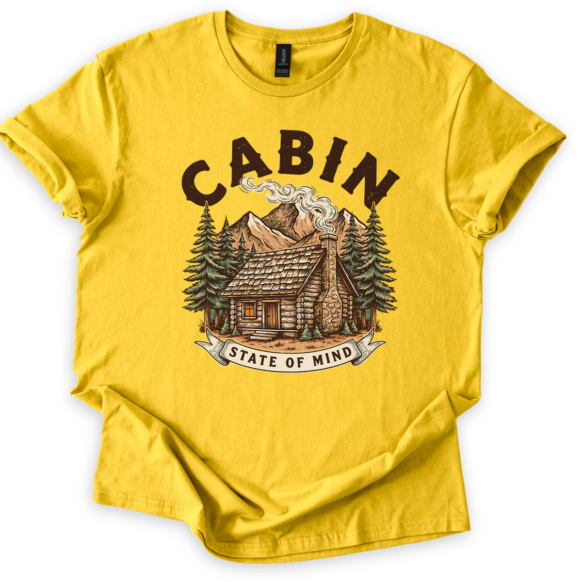 Cabin State Of Mind Comfort Colors T-shirt in Daisy, laid flat. CABIN arches in distressed dark brown letters over a log cabin with a smoking stone chimney, pine trees and mountains, above a banner reading STATE OF MIND. The shirt lies on white with cuffed sleeves.