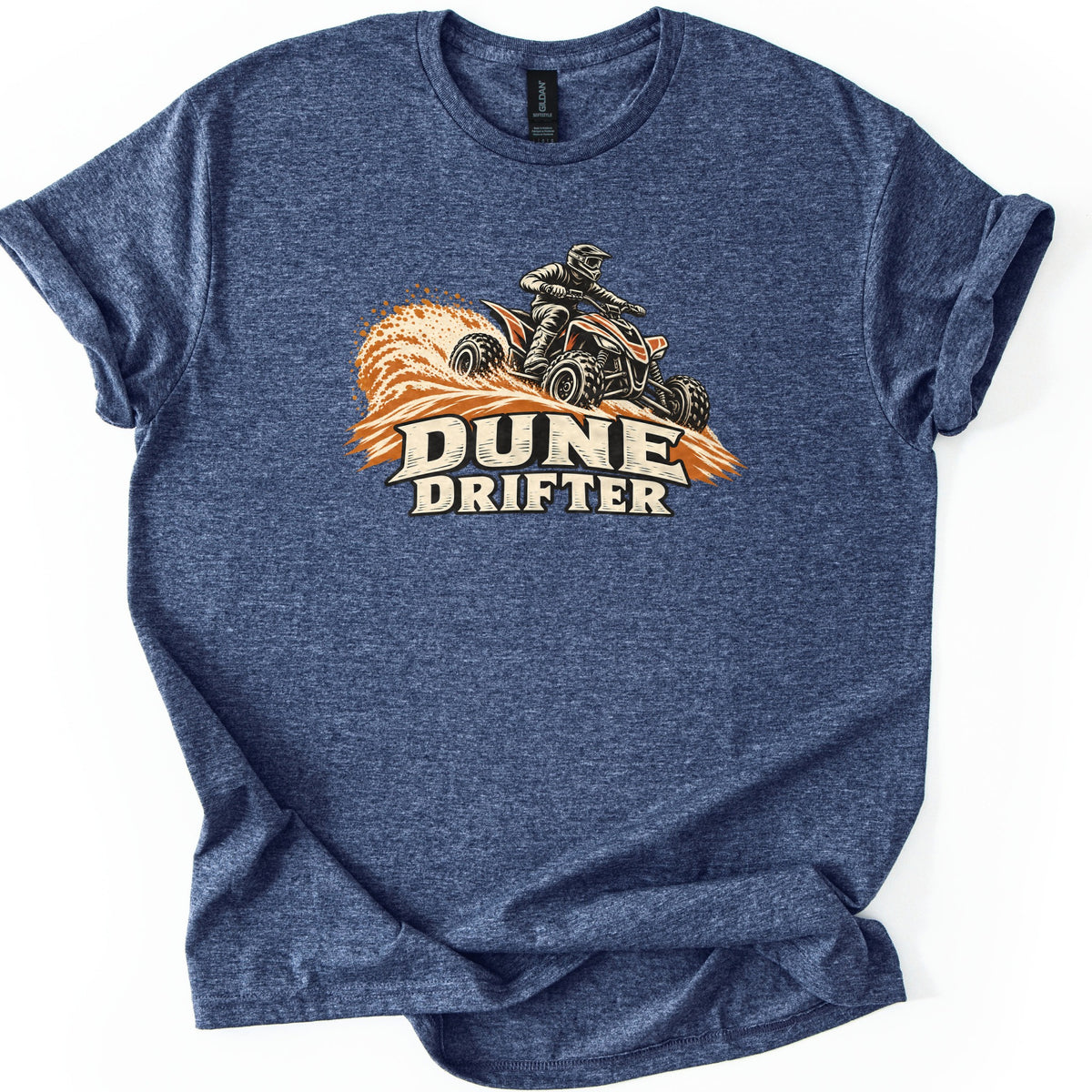 Dune Drifter Comfort Colors T-shirt in Heather Navy, laid flat. A helmeted rider on an orange and black ATV kicks up orange sand above the words Dune Drifter in cream letters. The shirt has cuffed sleeves and lies on a white background.