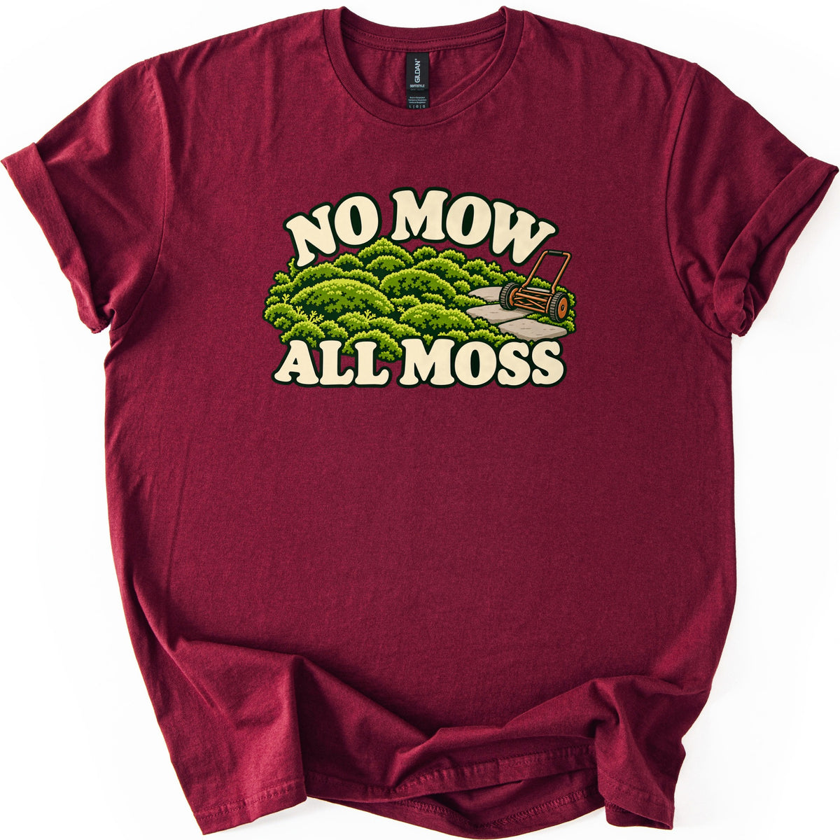 No Mow All Moss Comfort Colors T-shirt in Maroon, laid flat. Cream retro letters read No Mow above a cartoon of mounded green moss, a stone path and an old push reel mower, with All Moss below. The shirt lies on a white surface with cuffed sleeves.