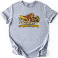 Landing Snack Inspector Comfort Colors T-shirt in Sport Grey, laid flat. A scruffy brown dog in a red life vest noses into an open green bag of snacks on a rocky riverbank by a yellow kayak, above the words Official Landing Snack Inspector. Sleeves rolled, on white.
