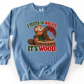 I Tested the Wreath. It's Wood. Comfort Colors crewneck sweatshirt in Blue Jean, laid flat. A cartoon beaver in a green apron holds a half-chewed twig wreath with a red bow and berries on a tree stump, between the words I Tested the Wreath. and It's Wood. Laid on a white background.