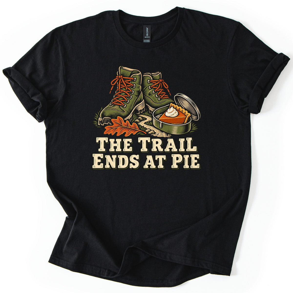 The Trail Ends at Pie Comfort Colors T-shirt in Black, laid flat. Green hiking boots with orange laces stand by an orange oak leaf and an open tin holding a slice of pumpkin pie with whipped cream, above the words The Trail Ends at Pie. Shown on white with rolled sleeves.