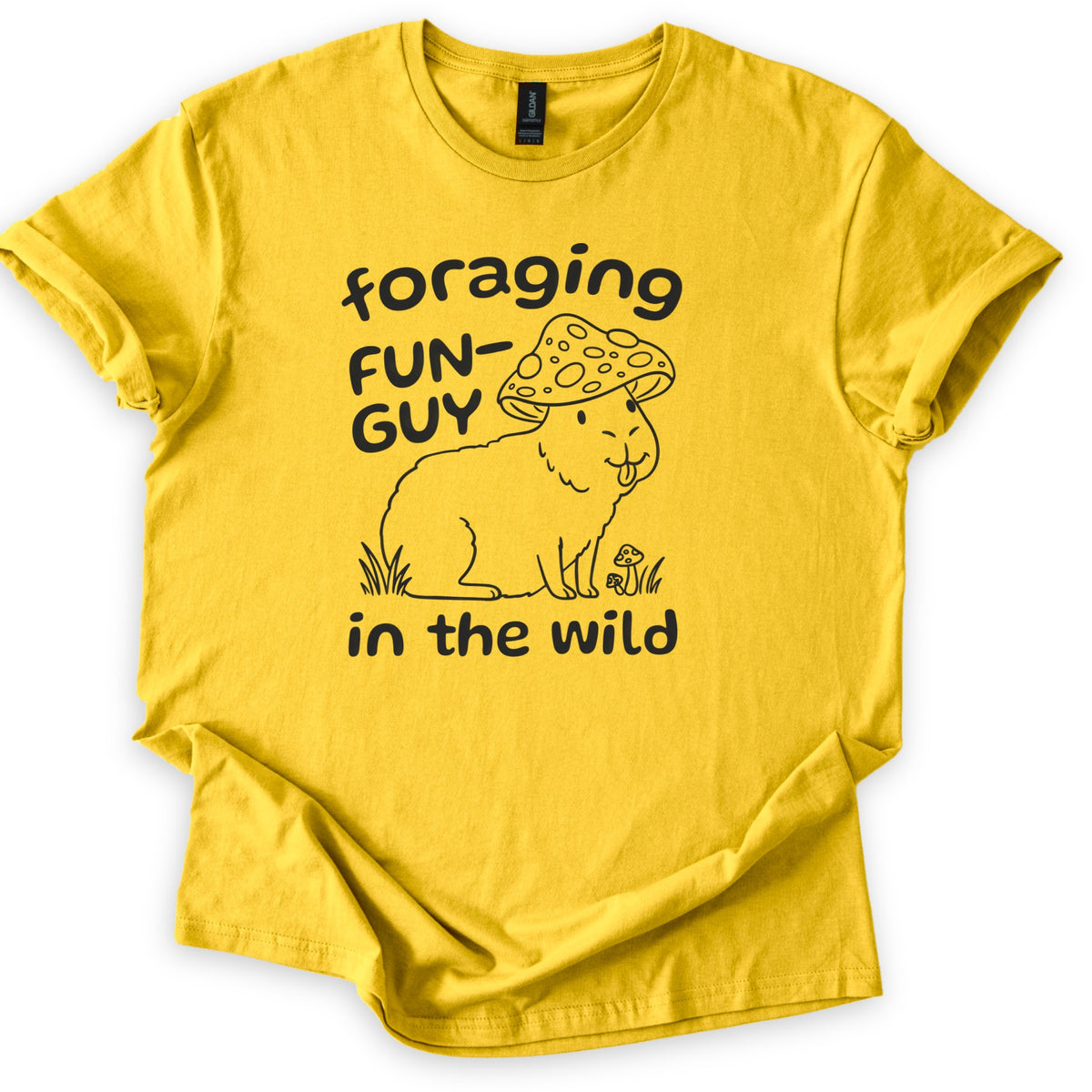Foraging Fun-Guy Capybara Comfort Colors T-shirt in Daisy, laid flat. A black line drawing of a winking capybara with its tongue out, wearing a spotted mushroom cap and sitting in grass by tiny mushrooms, with the words foraging FUN-GUY in the wild. Sleeves rolled, on white.