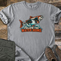 Follow the Water Home Comfort Colors T-shirt in Grey, laid flat. A salmon leaps from splashing water, its body filled with a forest and waterfall scene, above the words Follow the Water Home. Laid on wood planks beside folded olive hiking pants and brown hiking boots.