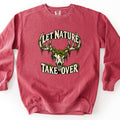 Let Nature Take Over Comfort Colors crewneck sweatshirt in Crimson, laid flat. A bleached deer skull with antlers draped in green moss sits between the words Let Nature arched above and Take Over below, in cream lettering. Shown on a plain white background.