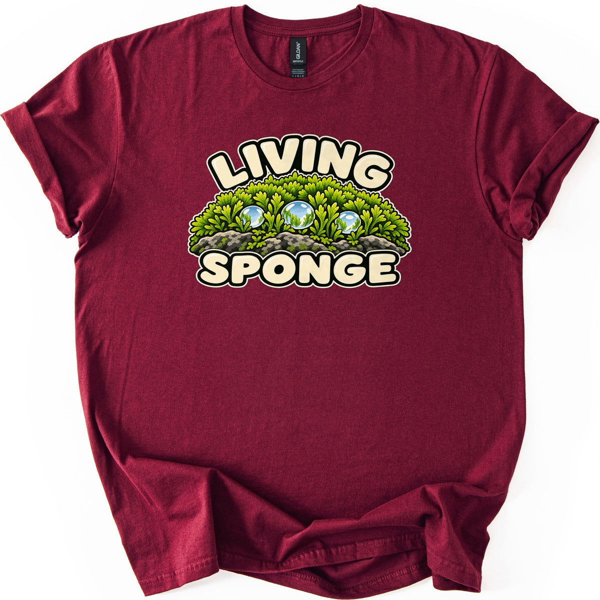 Living Sponge Comfort Colors T-shirt in Maroon, laid flat. A mound of bright green moss on gray rocks holding three clear water droplets, with LIVING arched above and SPONGE below in cream bubble letters. The shirt has cuffed sleeves on a white background.