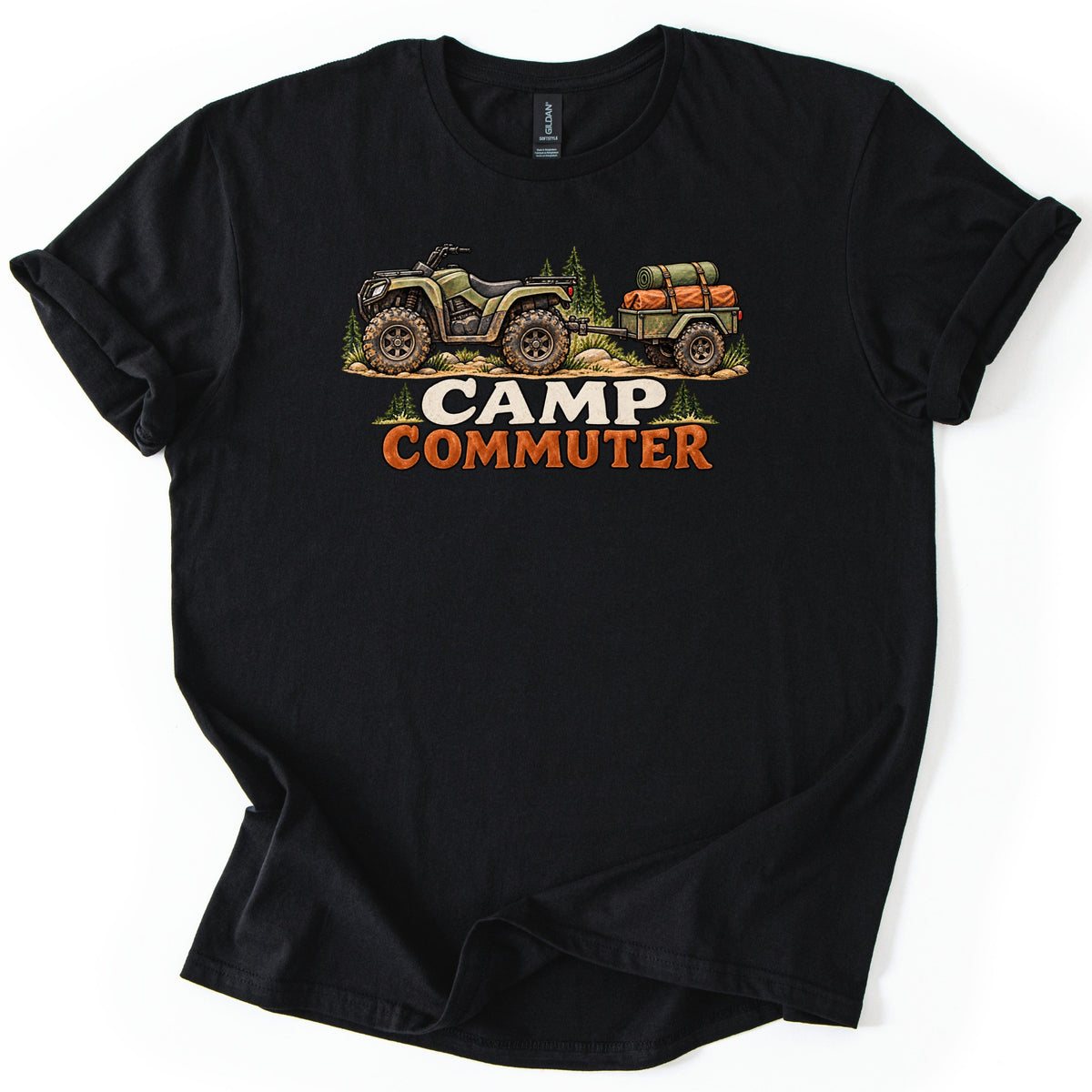Camp Commuter Comfort Colors T-shirt in Black, laid flat. A green ATV with mud-caked tires tows a small trailer loaded with an orange bag and green bedroll past pine trees, above the words Camp Commuter. The shirt has rolled sleeves on a white background.