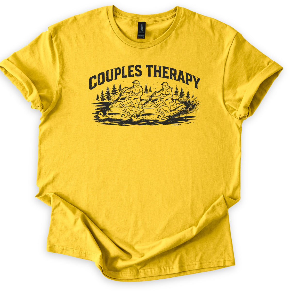 Couples Therapy Snowmobile Comfort Colors T-shirt in Daisy, laid flat. Black print of the arched words Couples Therapy above two helmeted riders on snowmobiles racing side by side through snow with pine trees behind. Sleeves are cuffed on a white background.