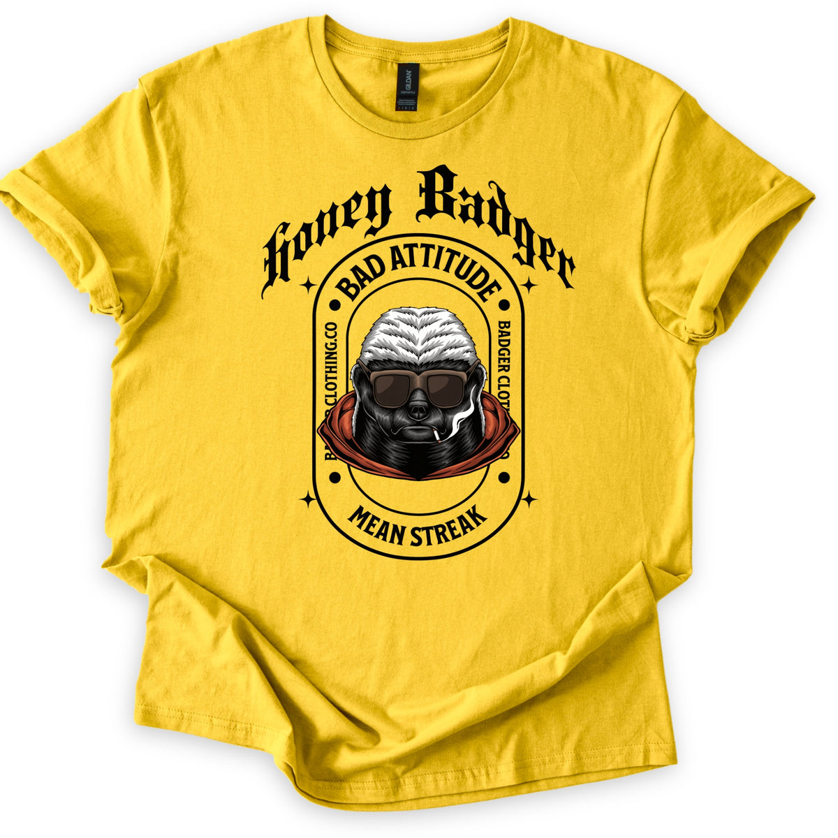 Bad Vibes Badger Comfort Colors T-shirt in Daisy, laid flat. Black print: Honey Badger in gothic letters over an oval badge reading Bad Attitude, Badger Clothing.co and Mean Streak around a honey badger in sunglasses and an orange hood, smoking a cigarette. On a white background.