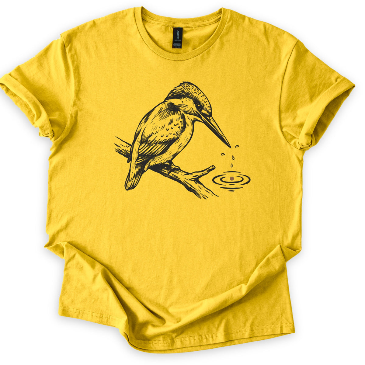 Kingfisher Comfort Colors T-shirt in Daisy, laid flat. A black ink drawing of a kingfisher perched on a branch, with droplets falling from its beak into rippling water below. The sleeves are cuffed and the shirt lies on a white background.