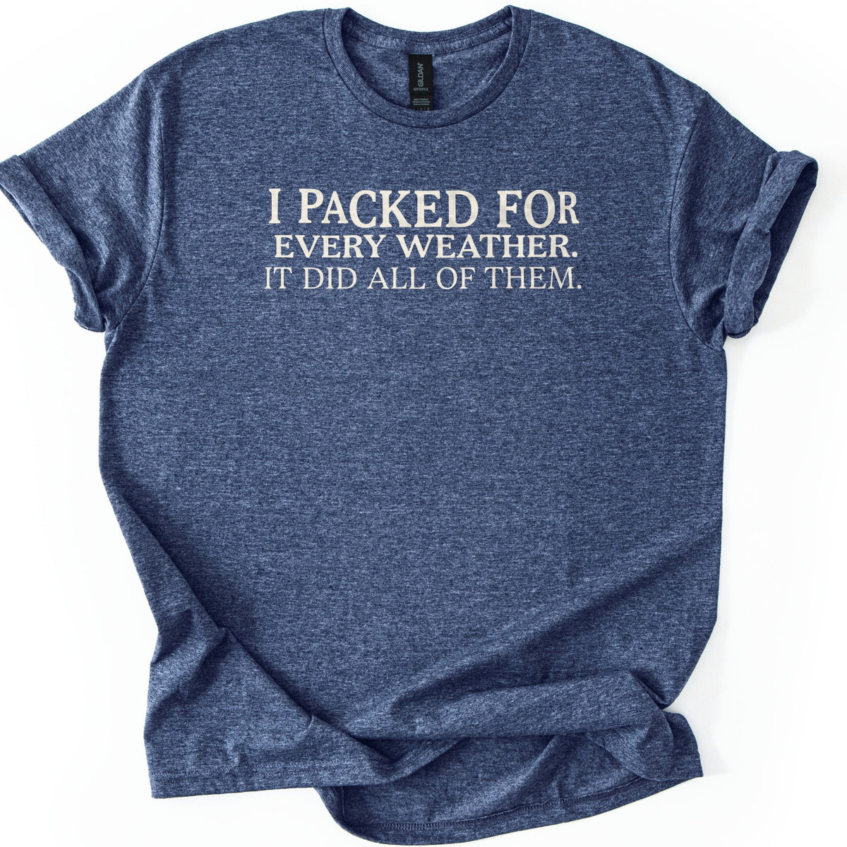 Packed For Every Weather Comfort Colors T-shirt in Heather Navy, laid flat. Off-white serif capital letters across the chest read I Packed For Every Weather. It Did All Of Them. The shirt lies on a white background with its sleeves cuffed and the hem loosely folded.