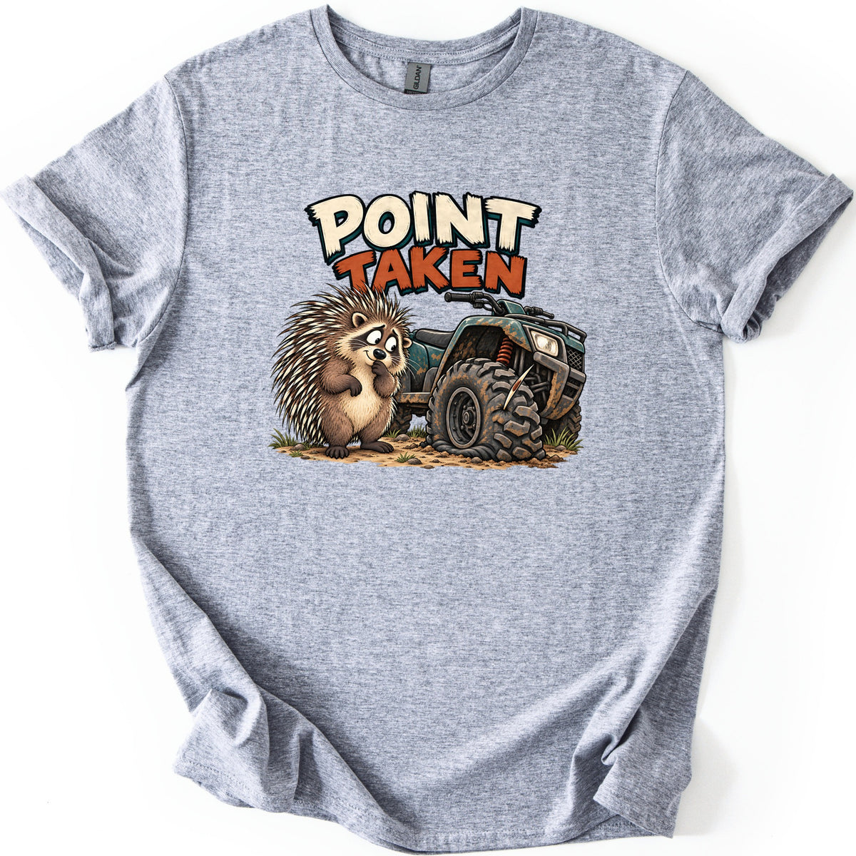 Point Taken Comfort Colors T-shirt in Sport Grey, laid flat. A cartoon porcupine holds a paw to its mouth beside a muddy green ATV with a quill stuck in its flat front tire, below the words Point Taken. The shirt lies on a white background with cuffed sleeves.