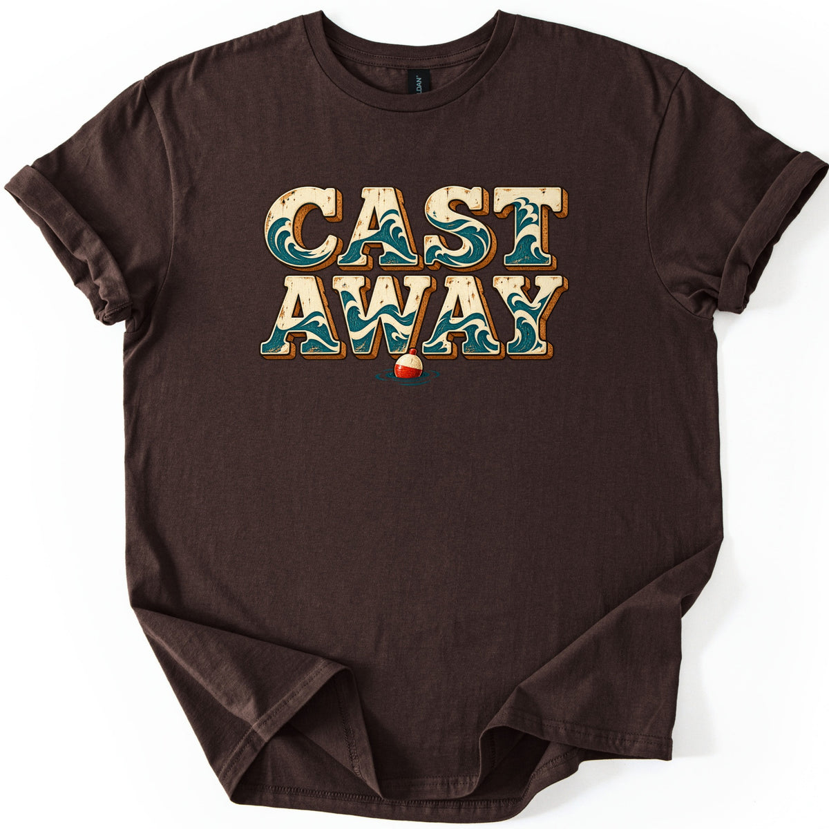 Cast Away Comfort Colors T-shirt in Dark Chocolate, laid flat. The words CAST AWAY in large cream block letters filled with teal ocean waves, with a red and white fishing bobber floating below. The shirt has rolled sleeves and lies on a white background.
