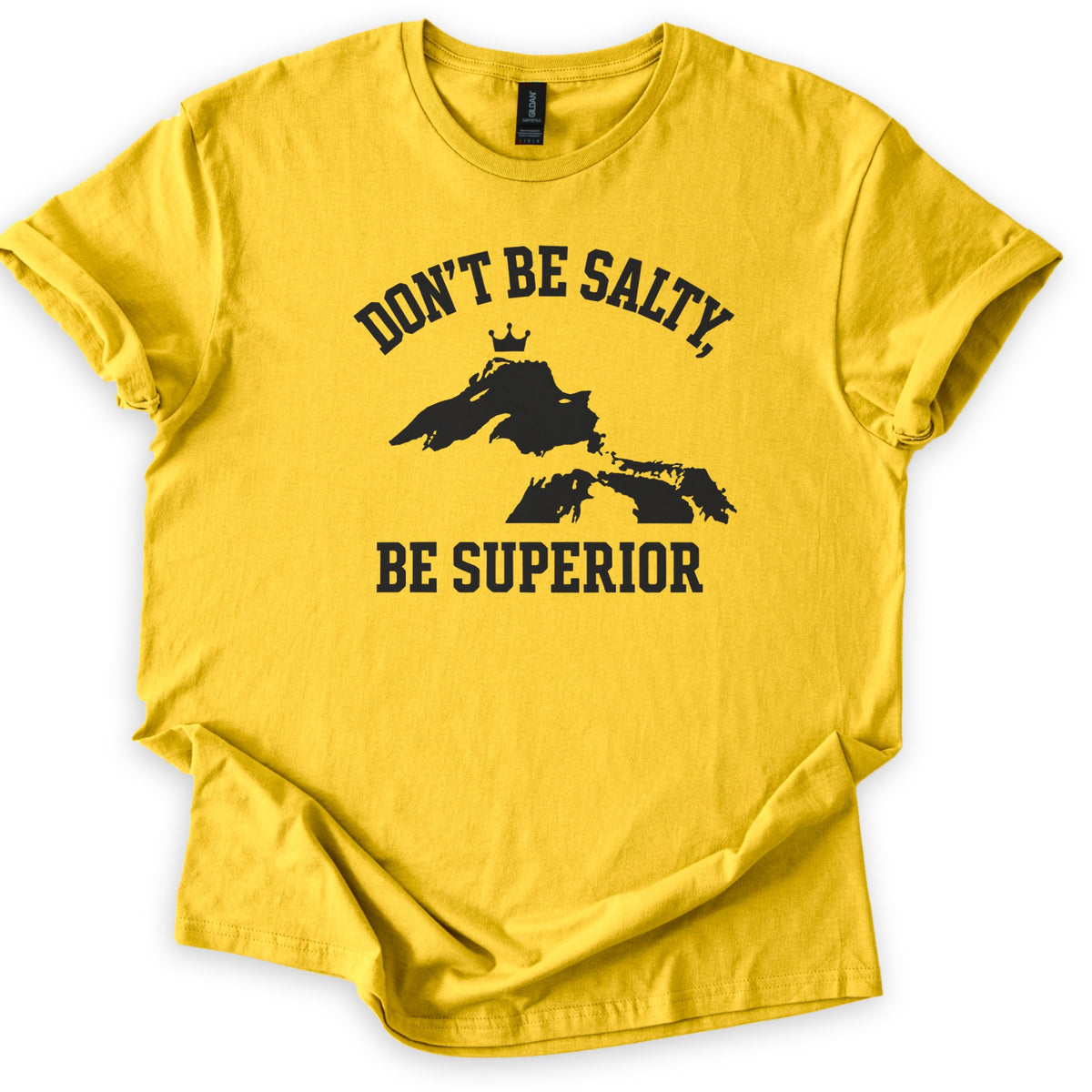 Be Superior Comfort Colors T-shirt in Daisy, laid flat. A black print shows the words Don't Be Salty, arched over a silhouette of the Great Lakes with a small crown above Lake Superior, and Be Superior below. Sleeves are cuffed on a white background.