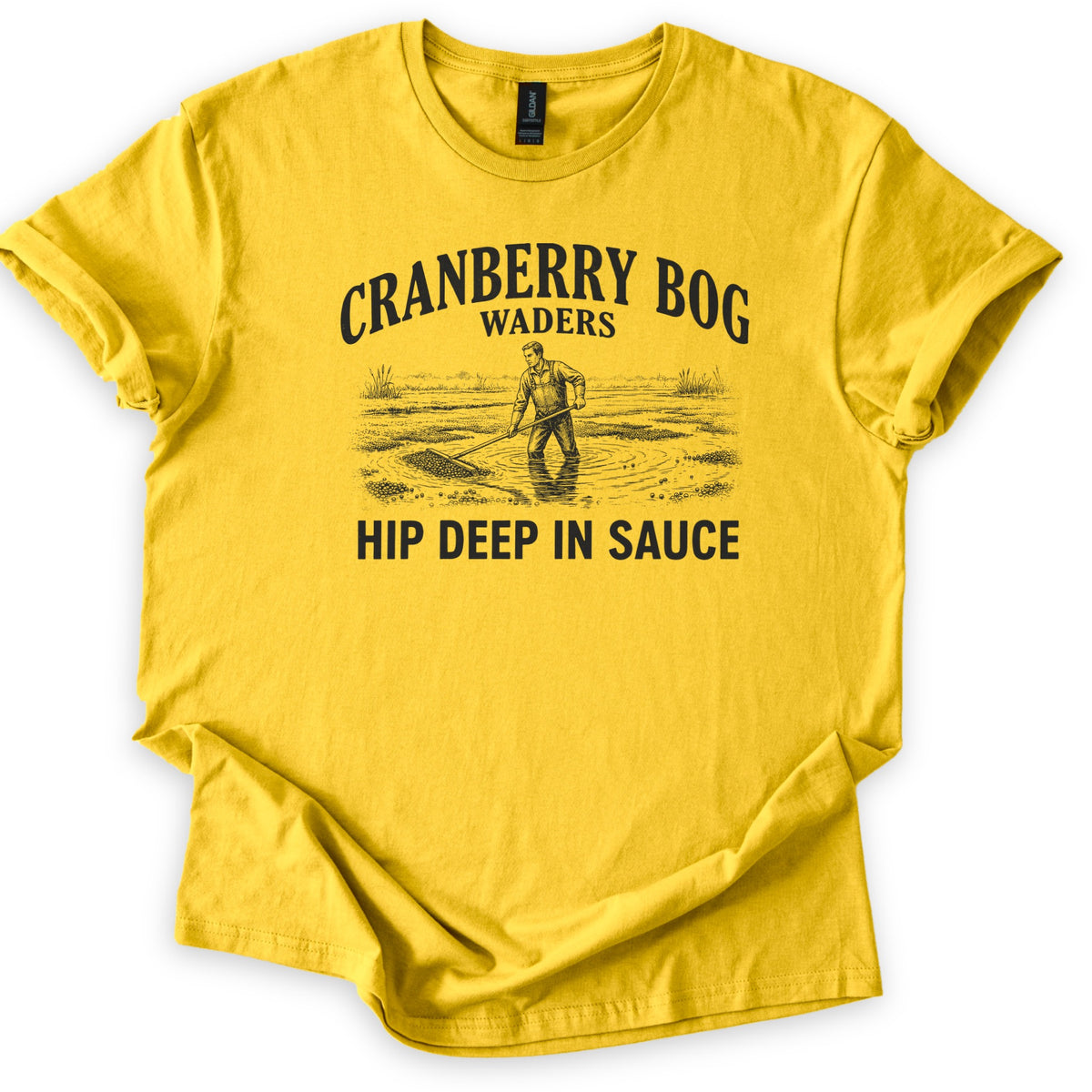 Cranberry Bog Waders Comfort Colors T-shirt in Daisy, laid flat. A black etched drawing of a man in overalls standing hip deep in a flooded bog, raking floating cranberries, under the words Cranberry Bog Waders and above Hip Deep in Sauce. Sleeves cuffed, on white.