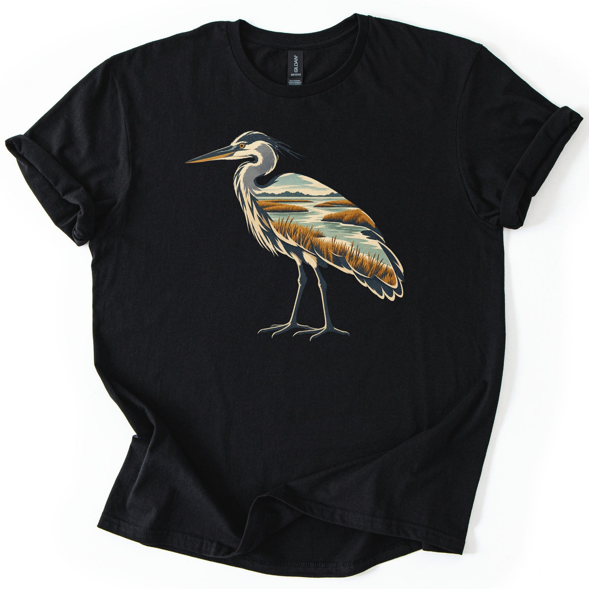 Heron Marsh Comfort Colors T-shirt in Black, laid flat. A standing heron in profile, its body filled with a marsh scene of winding water, golden grasses and distant hills. No words are printed. The sleeves are cuffed, on a white background.