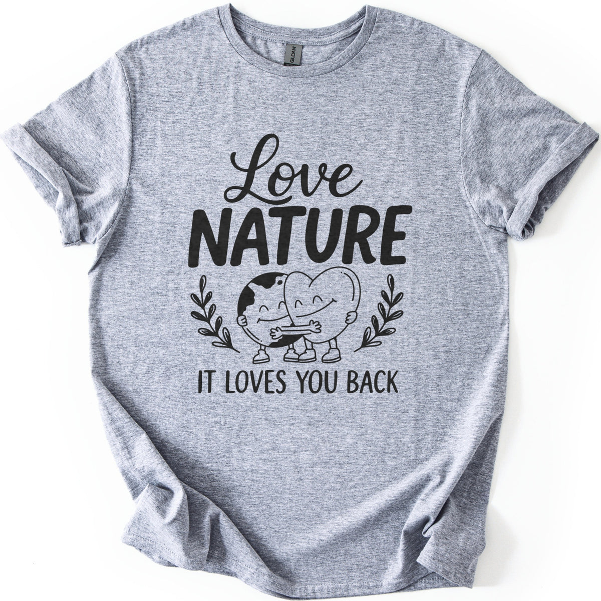 Nature Loves You Back Comfort Colors T-shirt in Sport Grey, laid flat. Black print reads Love NATURE above a smiling cartoon Earth and heart hugging between two leafy sprigs, then IT LOVES YOU BACK. The sleeves are rolled and the shirt lies on a white background.