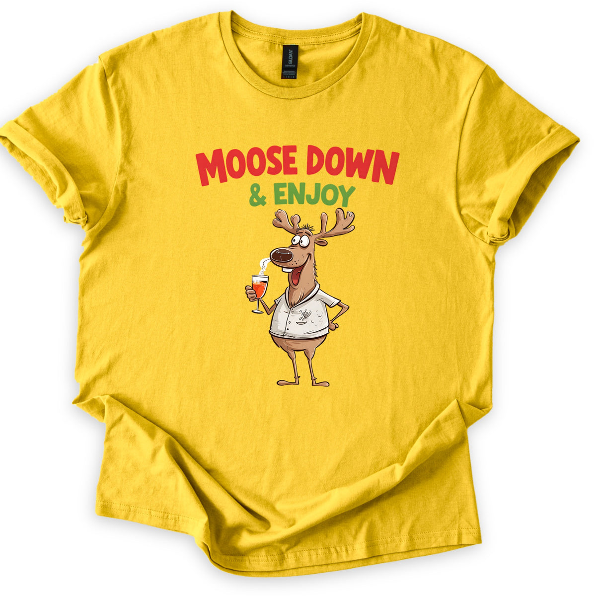 Moose Down And Enjoy Comfort Colors T-shirt in Daisy, laid flat. Red words Moose Down above green & Enjoy, over a grinning cartoon moose in a white short-sleeve shirt holding a glass of orange drink, hand on hip. Sleeves are cuffed on a white background.