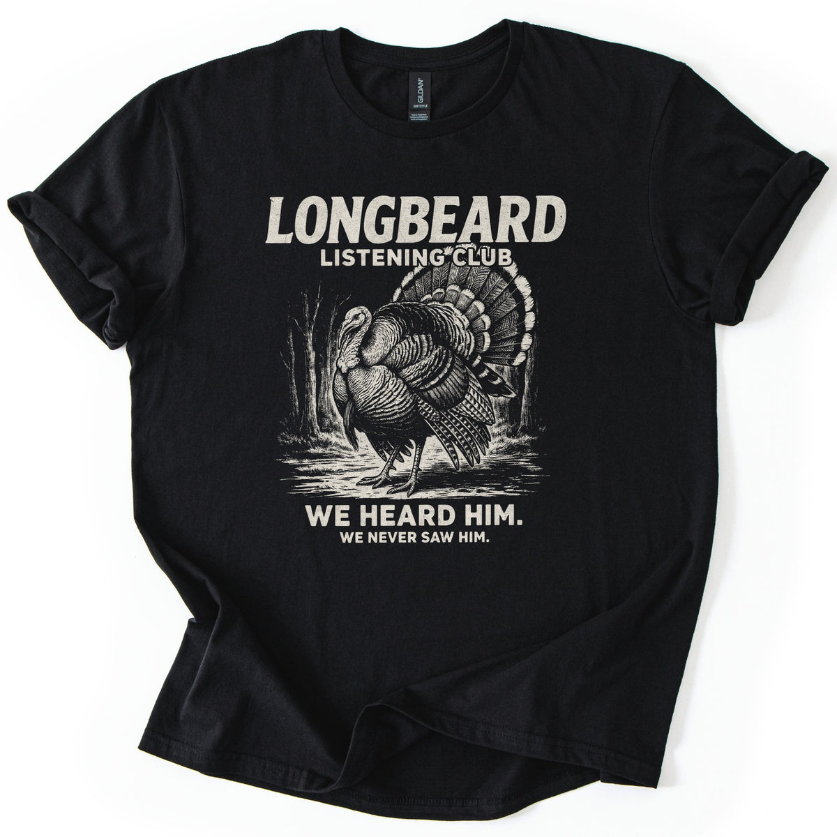 Longbeard Listening Club Comfort Colors T-shirt in Black, laid flat. Cream text reads LONGBEARD LISTENING CLUB above a detailed wild turkey with fanned tail among bare trees, then WE HEARD HIM. WE NEVER SAW HIM. The shirt has rolled sleeves on a white background.