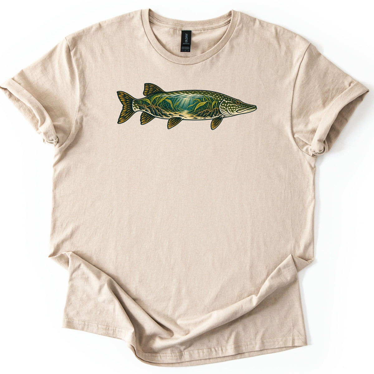 Pike Weed Bed Comfort Colors T-shirt in Sand, laid flat. A northern pike faces right across the chest, its body filled with an underwater scene of green weeds and sun rays over a sandy bottom, with gold fins. No words. Sleeves are cuffed on a white background.