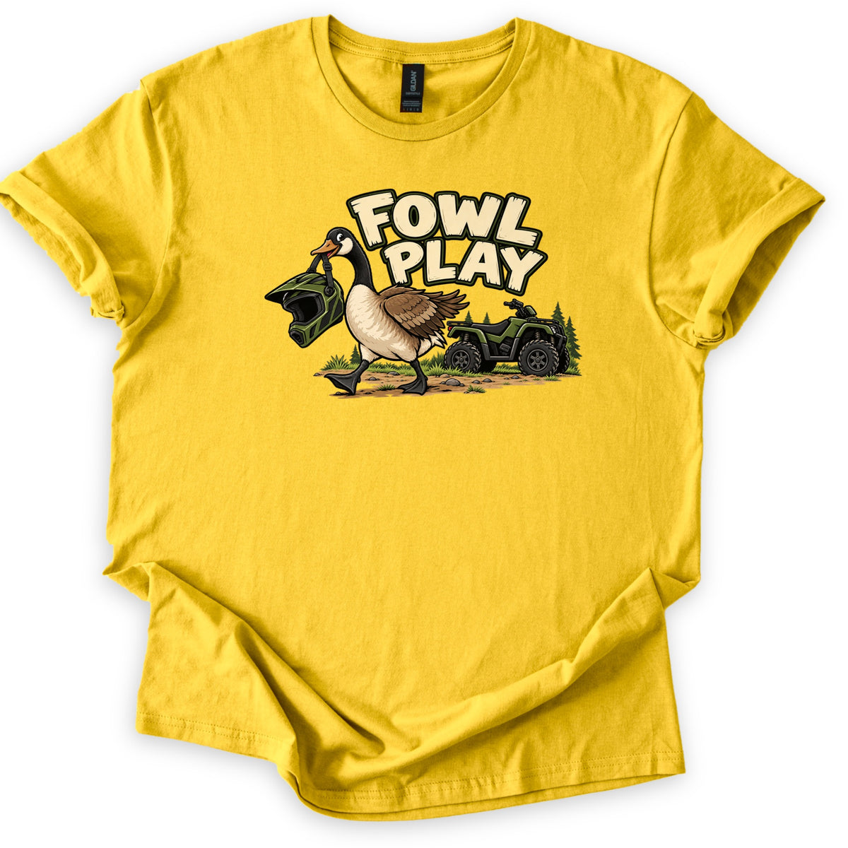 Fowl Play Comfort Colors T-shirt in Daisy, laid flat. A cartoon Canada goose carries a green motocross helmet in its beak past a green ATV and pine trees, below the words Fowl Play. The shirt lies on a white background with cuffed sleeves and a folded hem.