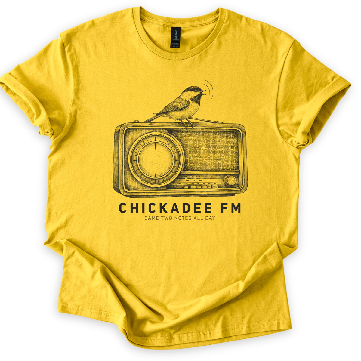 Chickadee FM Comfort Colors T-shirt in Daisy, laid flat. A sketched chickadee sings from atop a vintage radio above the words CHICKADEE FM and SAME TWO NOTES ALL DAY, printed in black on the yellow shirt. The sleeves are rolled, on a white background.