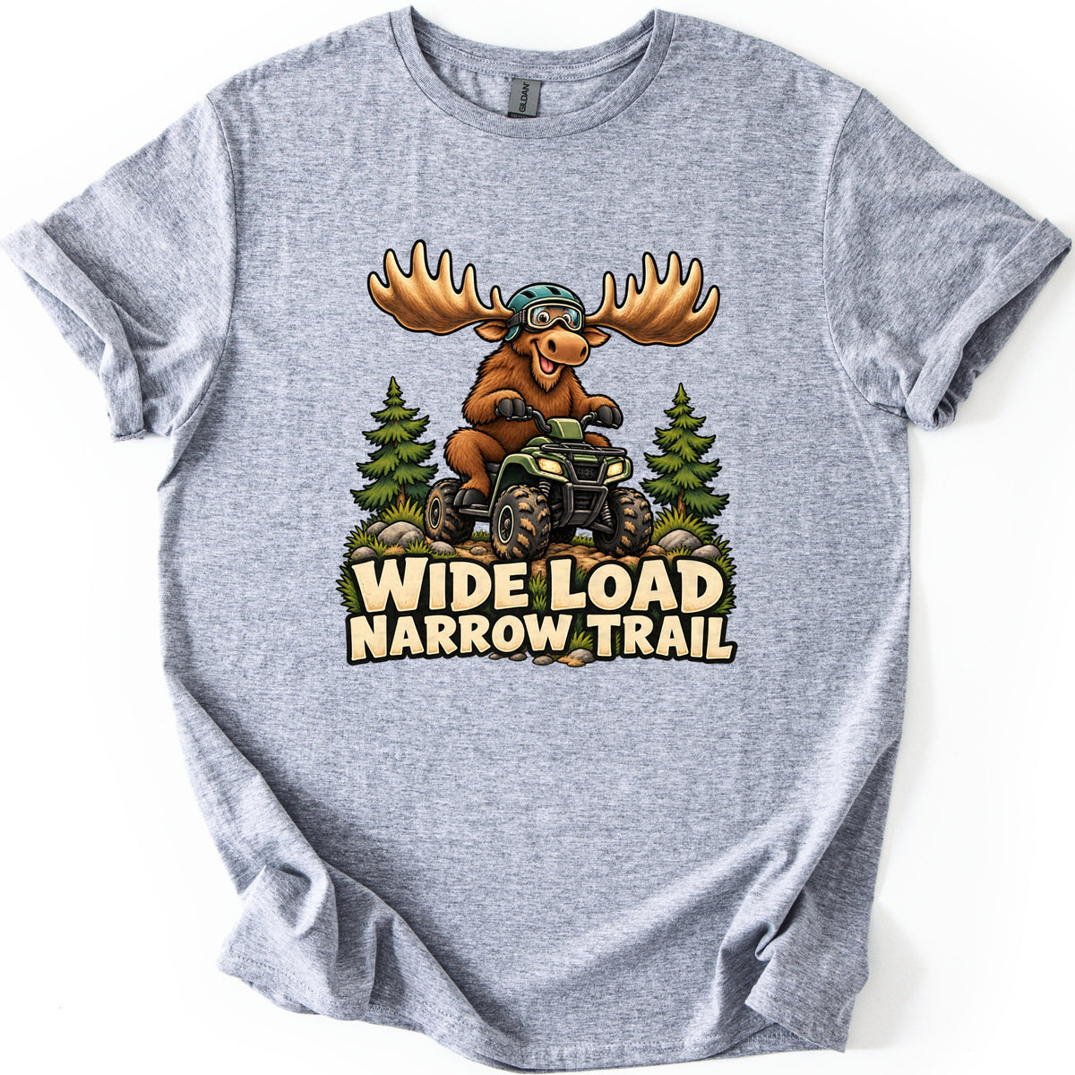 Wide Load Narrow Trail Comfort Colors T-shirt in Sport Grey, laid flat. A cartoon moose with huge antlers, a helmet and goggles rides a green ATV on a dirt trail between pine trees above the words Wide Load Narrow Trail. The shirt lies on a white background with cuffed sleeves.