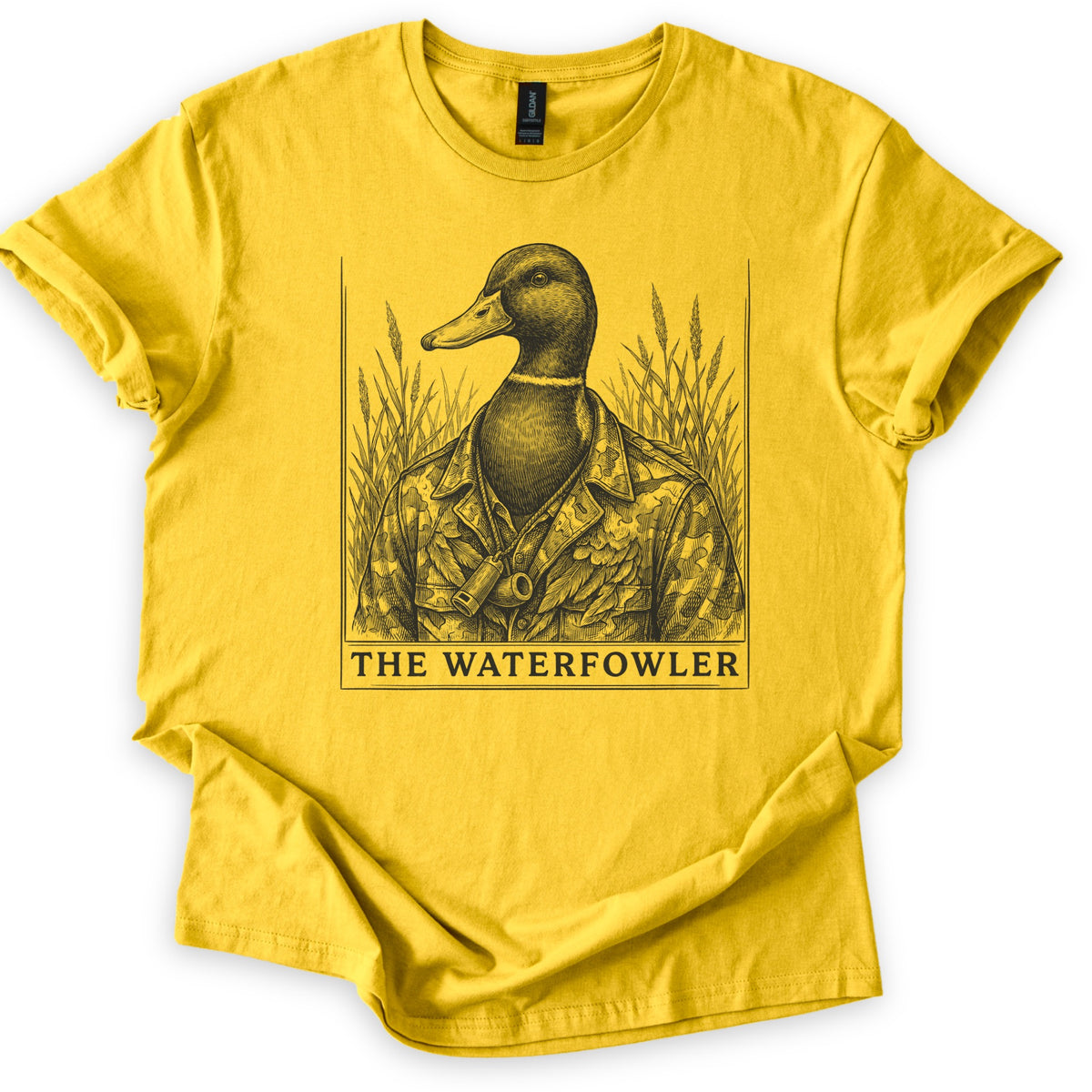 The Waterfowler Comfort Colors T-shirt in Daisy, laid flat. A black engraving-style drawing of a mallard duck in a camo shirt with a duck call on a lanyard, set in tall marsh grass inside a thin frame, above the words THE WATERFOWLER. Sleeves cuffed, on white.