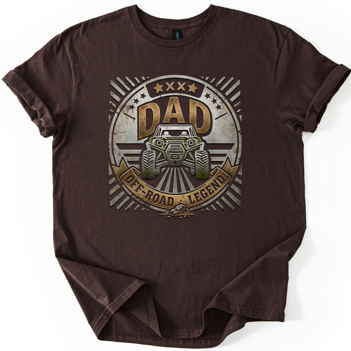 Dad Off Road Legend Comfort Colors T-shirt in Dark Chocolate, laid flat. A distressed round badge with sunburst rays and stars shows the word DAD above a green off-road buggy, with a gold banner reading OFF-ROAD LEGEND. The shirt lies on a white background with rolled sleeves.