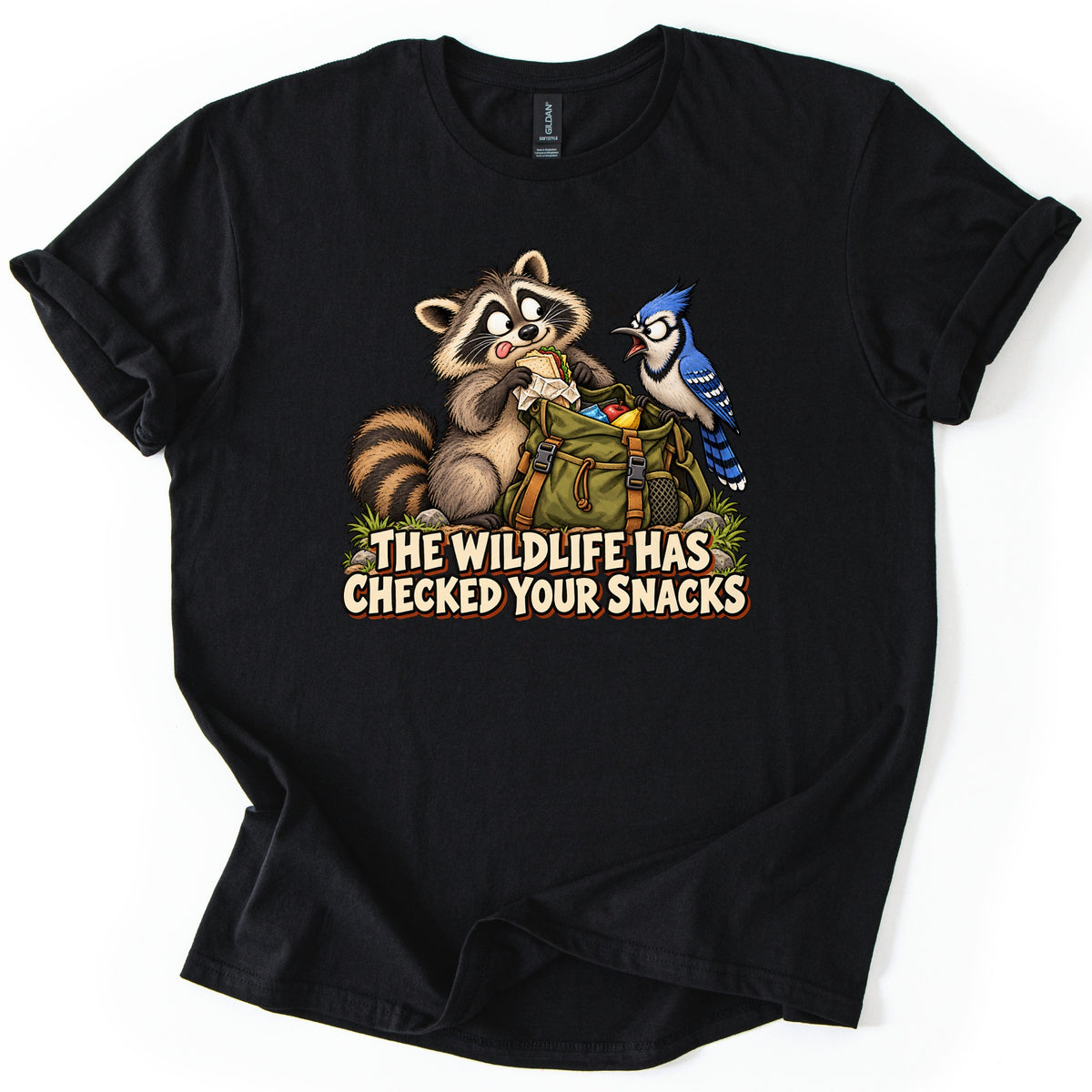 The Wildlife Has Checked Your Snacks Comfort Colors T-shirt in Black, laid flat. A cartoon raccoon eats a sandwich from an open green backpack while a blue jay squawks at it, above the words The Wildlife Has Checked Your Snacks. The shirt has rolled sleeves on a white background.