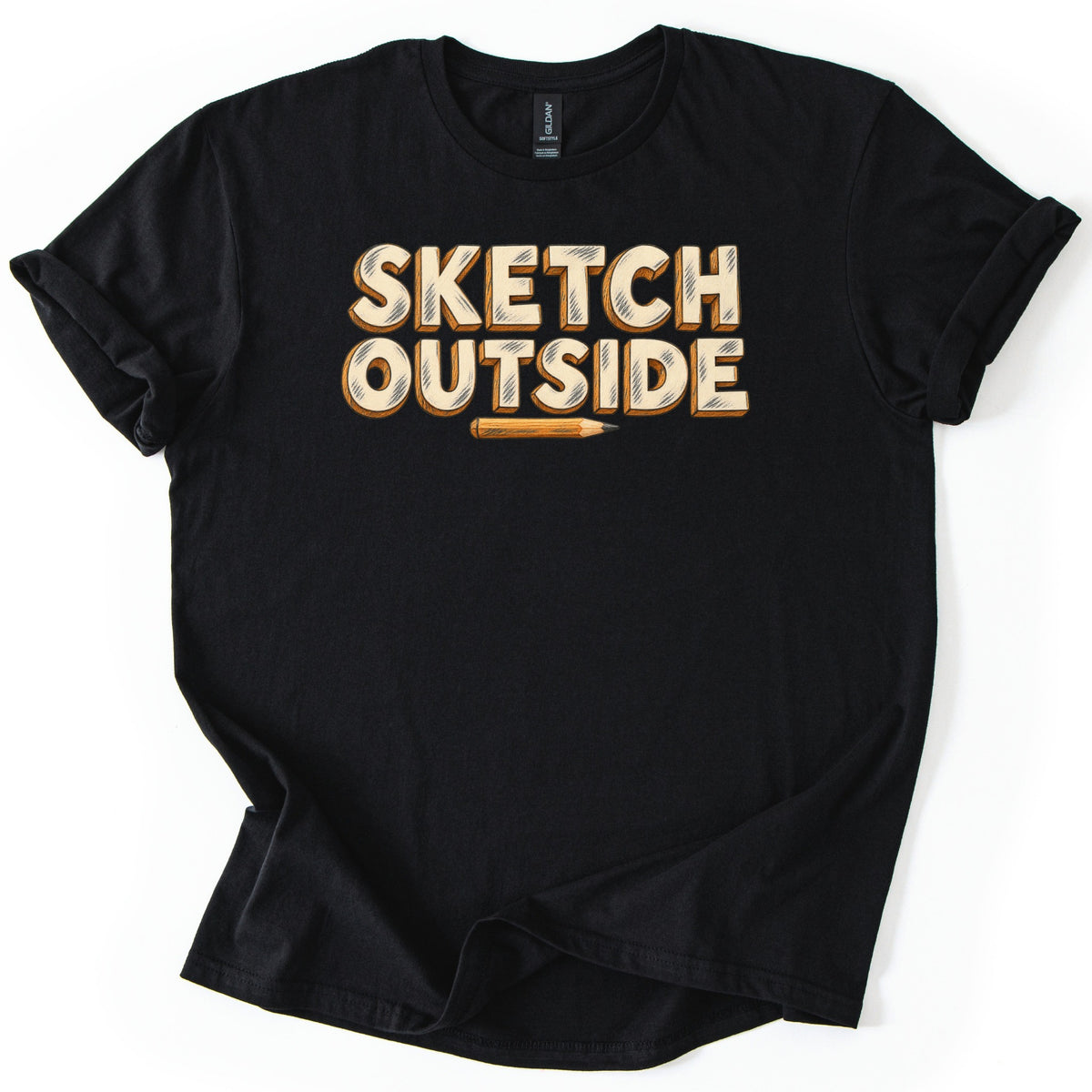 Sketch Outside Comfort Colors T-shirt in Black, laid flat. Sketch Outside is printed in cream block letters with orange shadows and sketchy pencil shading, with a small sharpened pencil underneath. The shirt lies on a white background with its sleeves rolled.