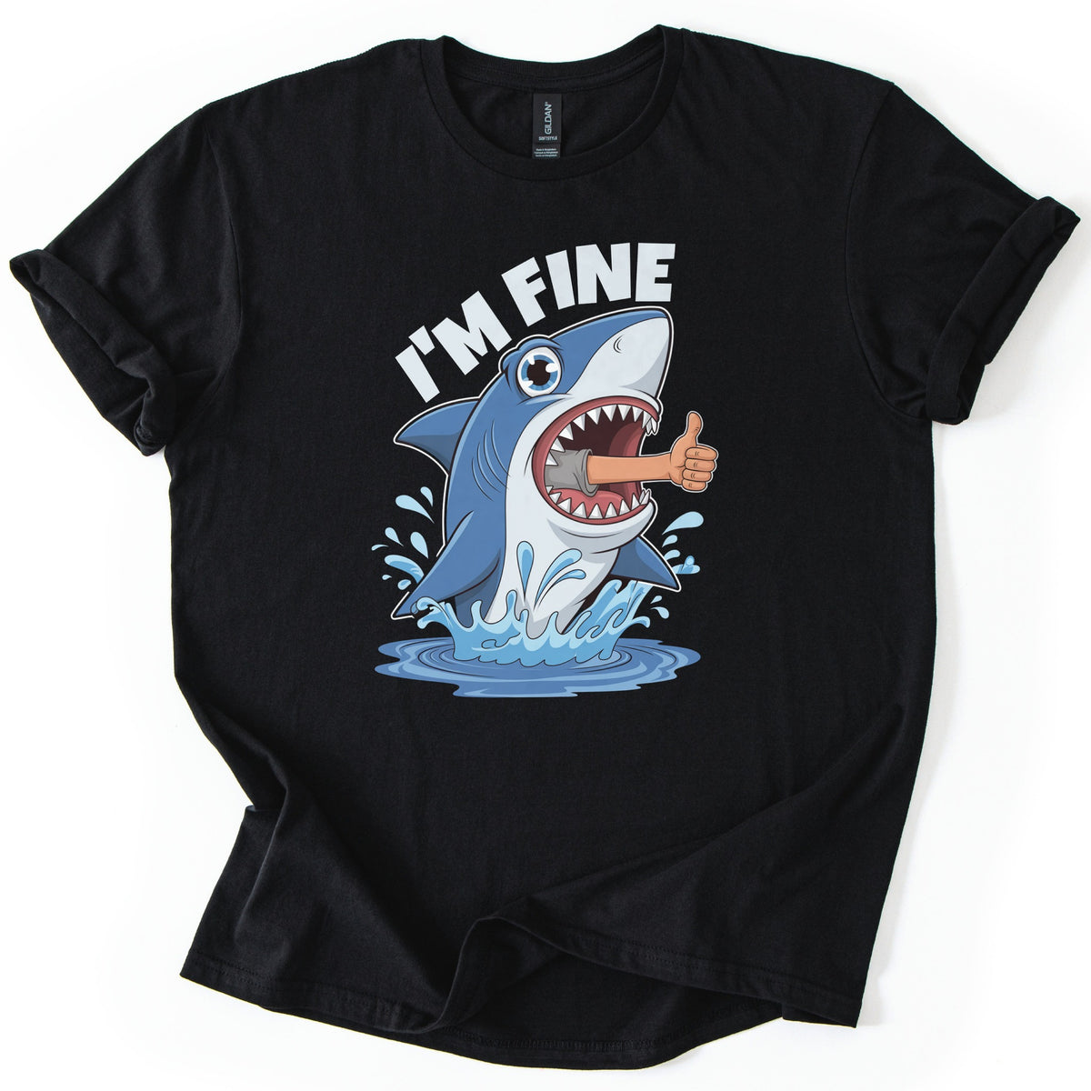 Shark I'm Fine Comfort Colors T-shirt in Black, laid flat. A cartoon blue shark leaps from splashing water with a human arm giving a thumbs up sticking out of its open mouth, under the words I'M FINE in white. The shirt has rolled sleeves on a white background.