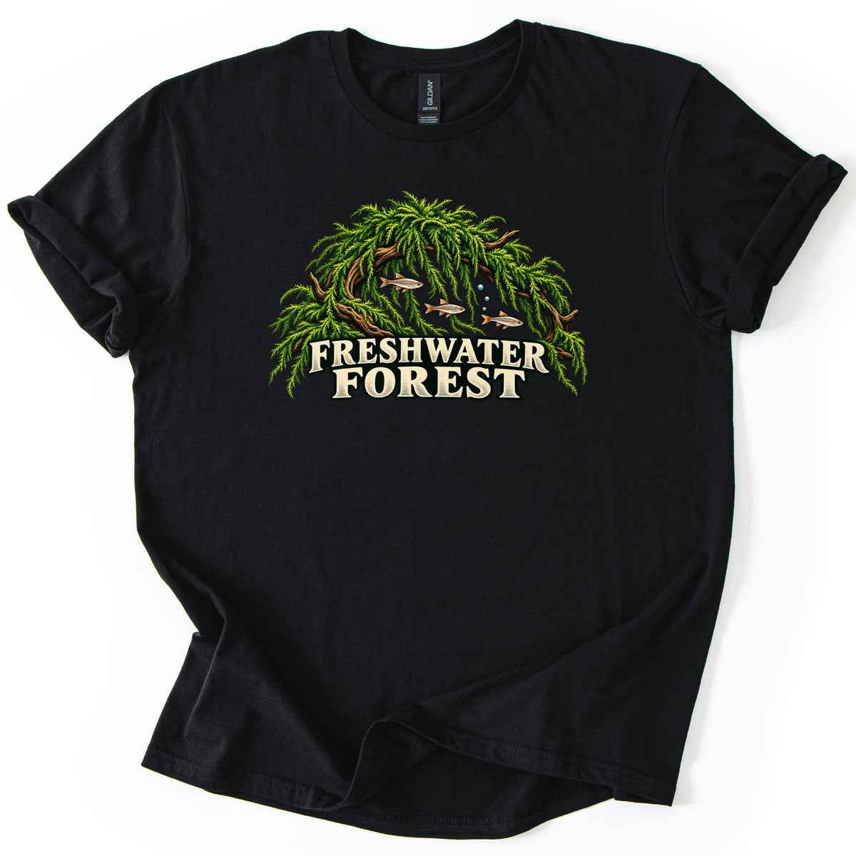 Freshwater Forest Comfort Colors T-shirt in Black, laid flat. An arch of driftwood draped in bright green aquarium moss shelters three small fish and rising bubbles, above the words Freshwater Forest in cream lettering. The sleeves are rolled on a white background.