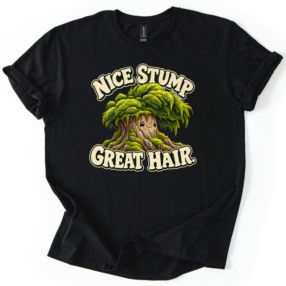 Nice Stump Great Hair Comfort Colors T-shirt in Black, laid flat. A smiling cartoon tree stump with a thick mop of green moss like hair, between the words Nice Stump and Great Hair. in cream letters. The shirt has rolled sleeves and lies on a white background.