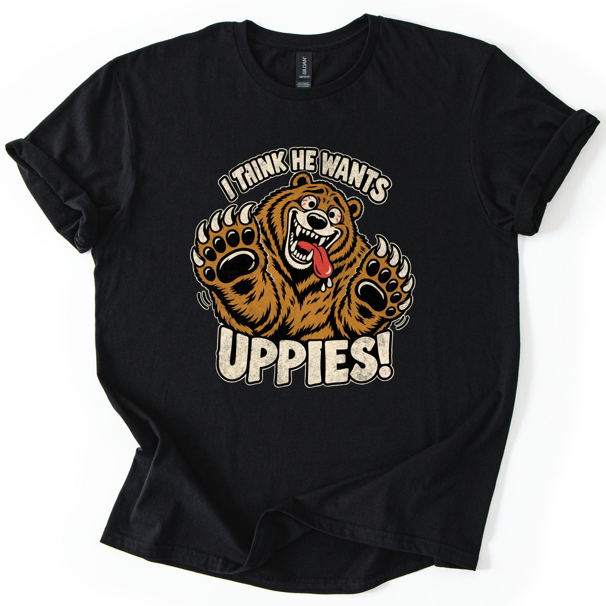 I Think He Wants Uppies Comfort Colors T-shirt in Black, laid flat. A grinning cartoon brown bear with bulging eyes and a drooling tongue reaches up with both clawed paws between the words I Think He Wants and Uppies! The sleeves are cuffed on a white background.