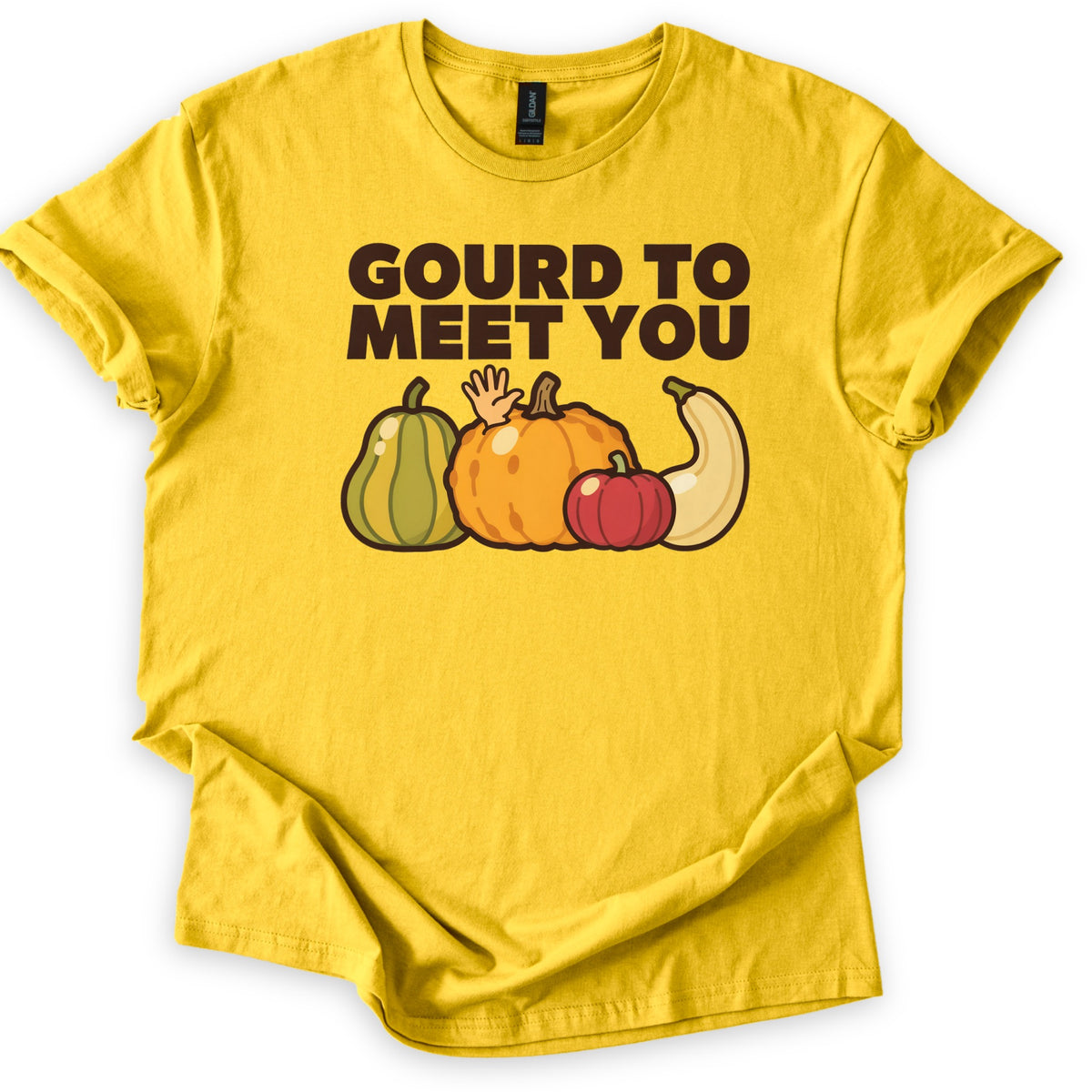 Gourd To Meet You Comfort Colors T-shirt in Daisy, laid flat. Dark brown block letters read GOURD TO MEET YOU above cartoon gourds: a green striped squash, a bumpy orange pumpkin with a hand waving behind it, a small red pumpkin and a curved cream squash. Sleeves cuffed, on white.