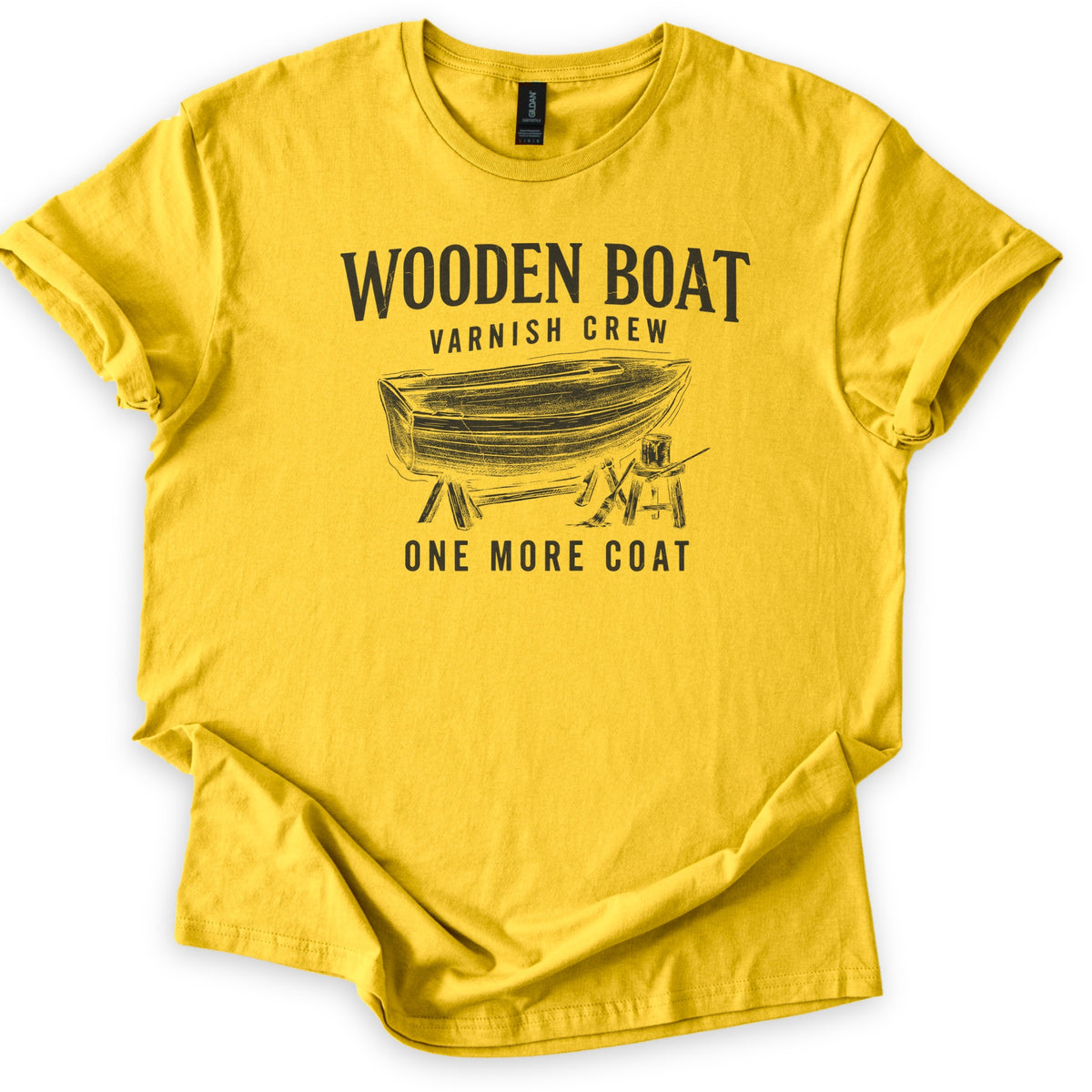 Wooden Boat Varnish Crew Comfort Colors T-shirt in Daisy, laid flat. Black print reads Wooden Boat, Varnish Crew above a sketch of a wooden rowboat on sawhorses beside a stool with a varnish can and brush, then One More Coat. Sleeves cuffed on a white background.