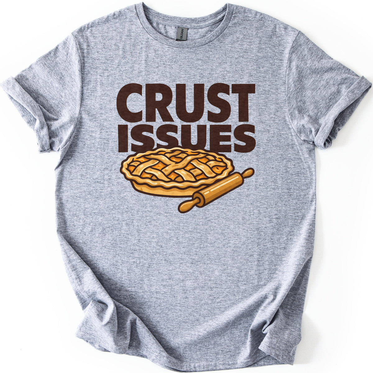 Crust Issues Comfort Colors T-shirt in Sport Grey, laid flat. Dark brown block letters read CRUST ISSUES above a cartoon lattice-top pie with a wooden rolling pin. The shirt has rolled sleeves and lies on a plain white background.