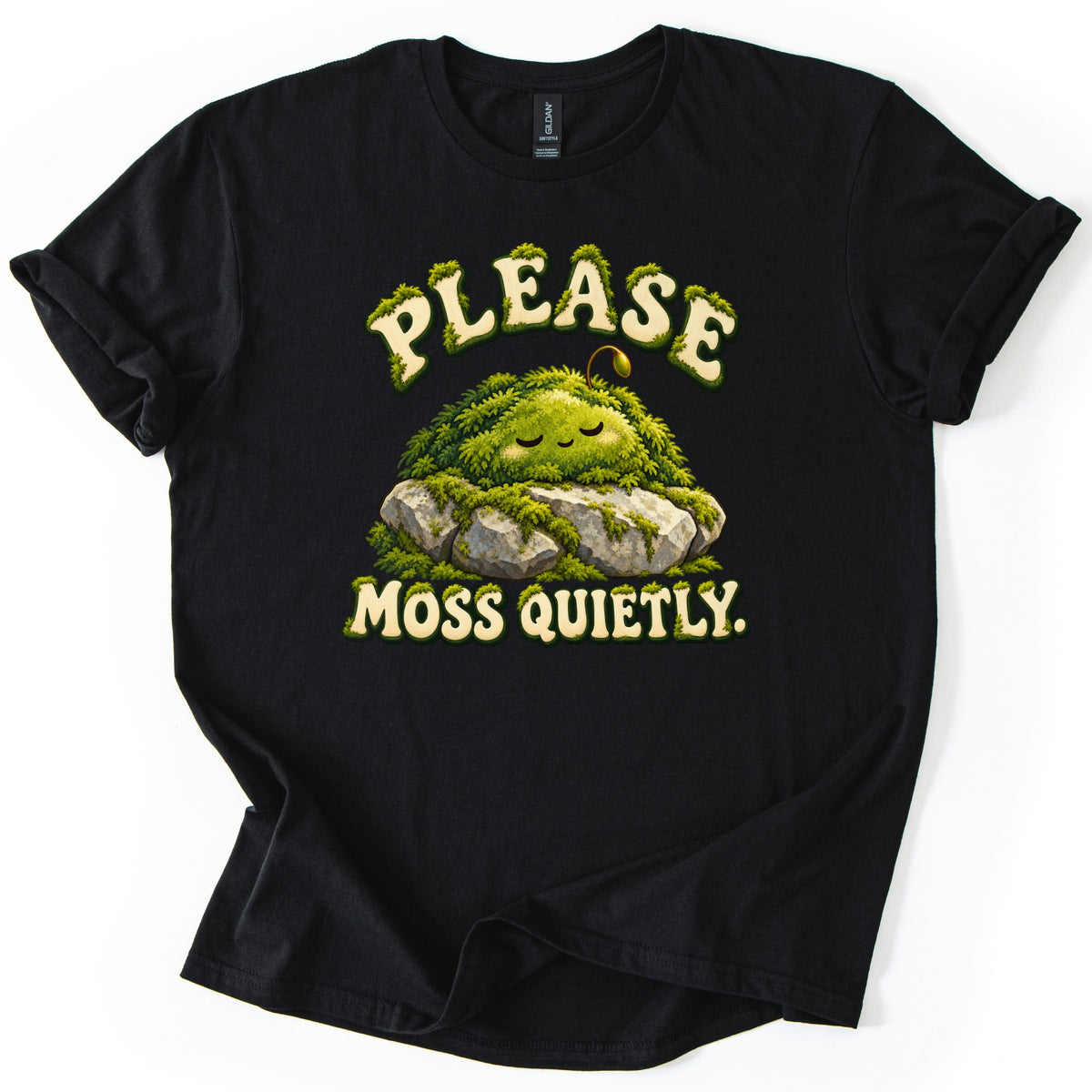 Please Moss Quietly Comfort Colors T-shirt in Black, laid flat. A sleepy, smiling mound of green moss with a tiny sprout rests on gray rocks between the words Please Moss Quietly. in cream letters edged with moss. The sleeves are rolled on a white background.