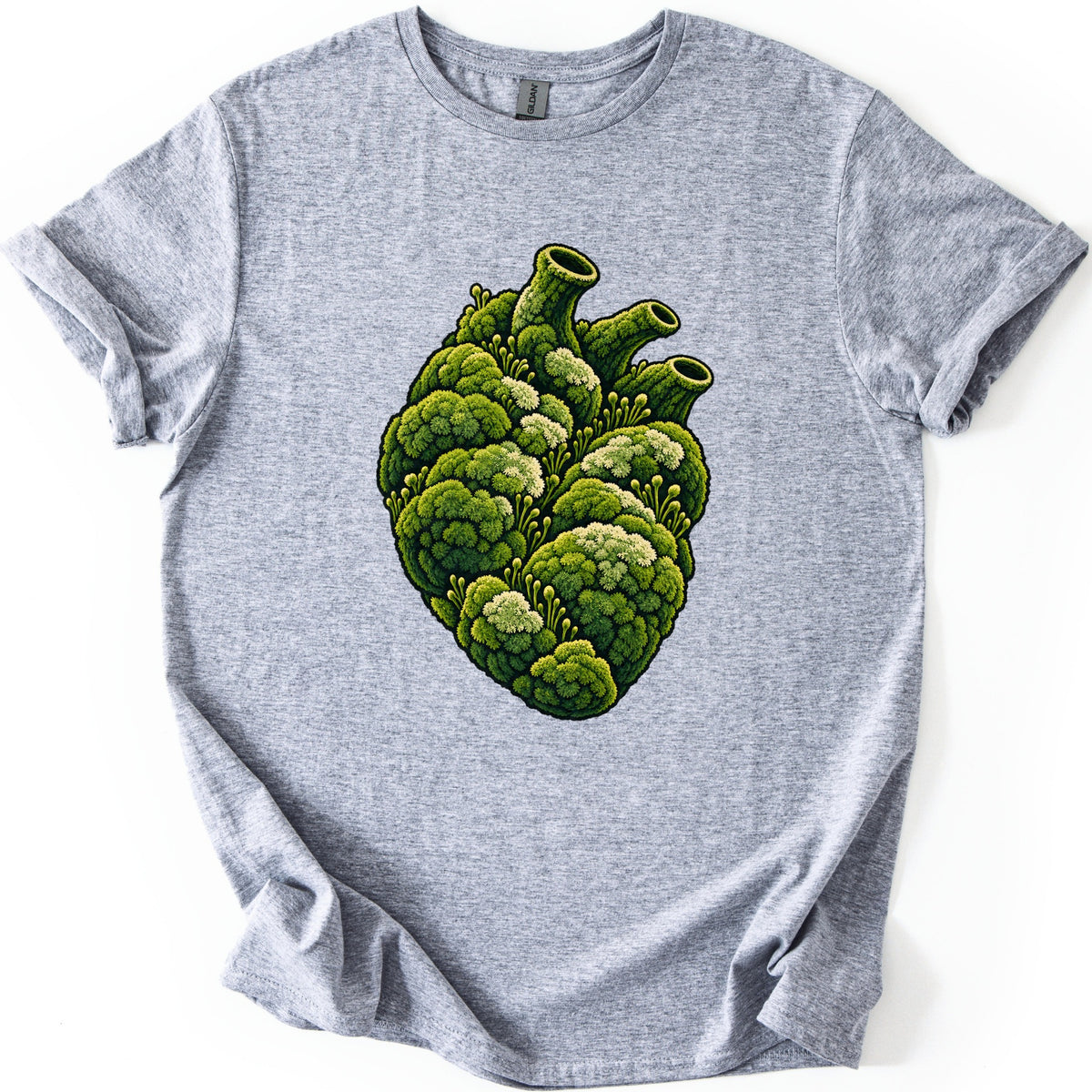 Moss Heart Comfort Colors T-shirt in Sport Grey, laid flat. An anatomical heart made of clumps of green moss, with pale tufts, small sprouting stalks and three tube-like vessels on top, with no words. The shirt lies on a white surface with sleeves cuffed.