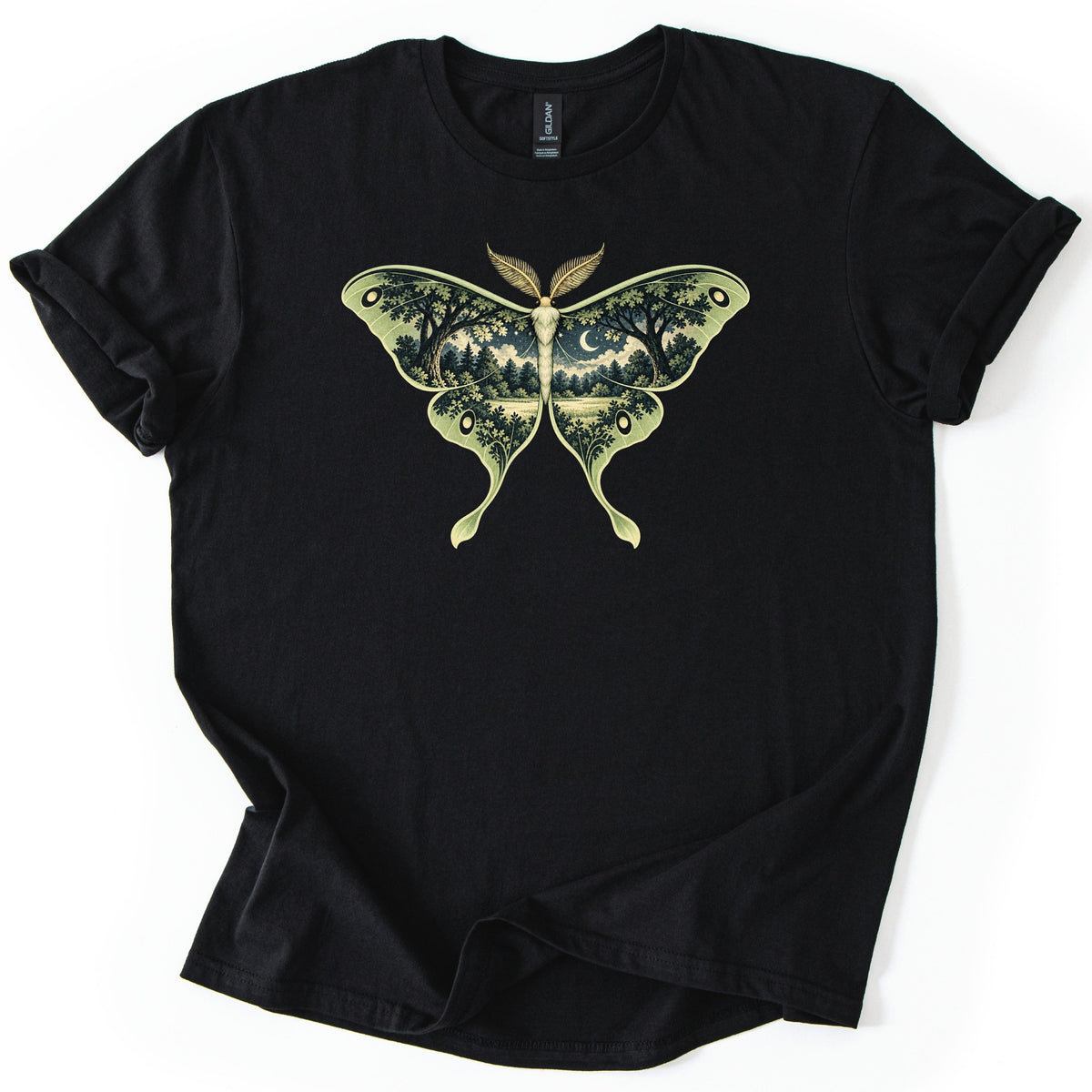 Luna Moth Night Comfort Colors T-shirt in Black, laid flat. A large green luna moth is printed on the chest, its wings filled with a night forest scene of trees, a meadow and a crescent moon. No words are printed. The shirt has rolled sleeves on a white background.