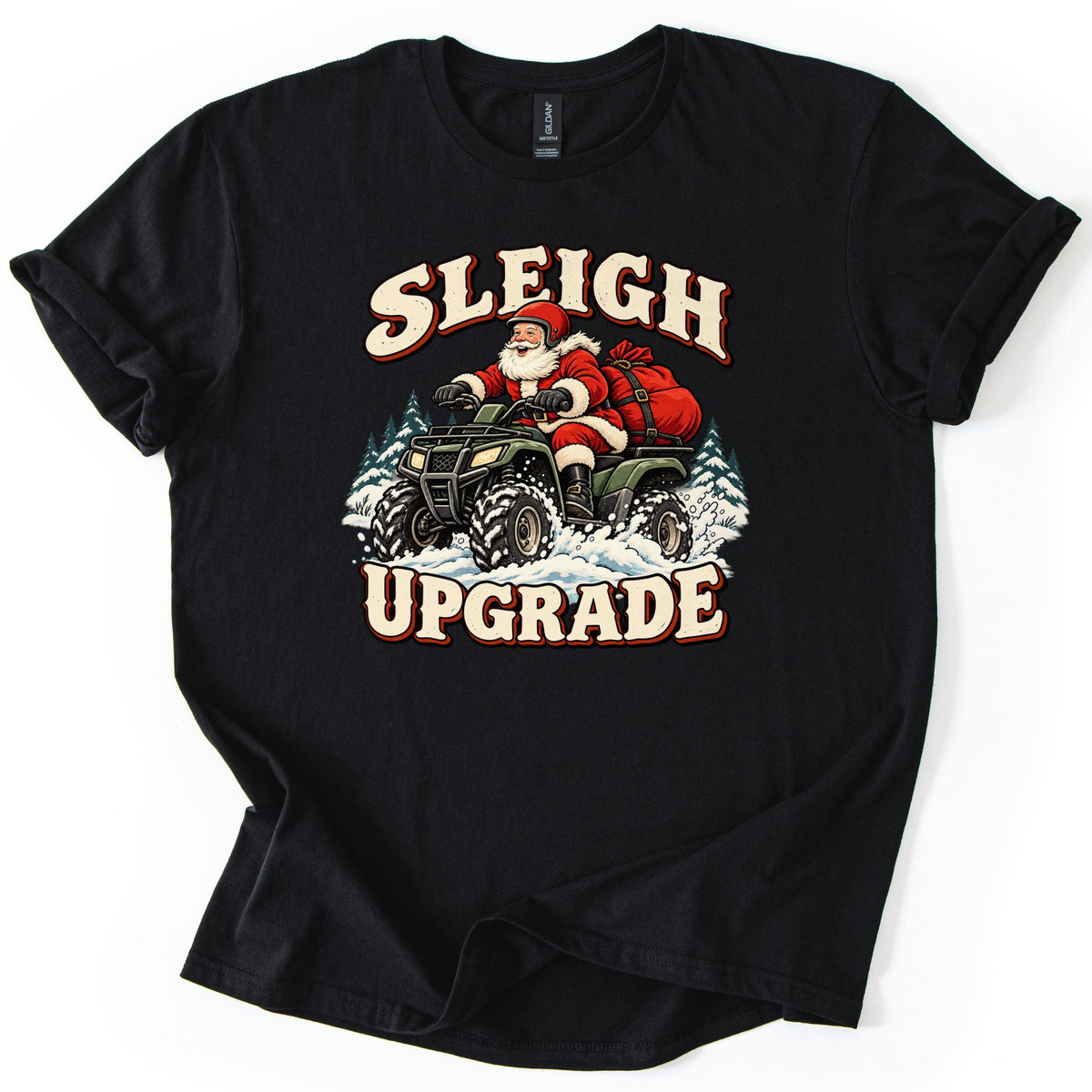 Sleigh Upgrade Comfort Colors T-shirt in Black, laid flat. Santa in a red helmet drives a green ATV through snowy pines, a red sack strapped on back, under Sleigh and above Upgrade in cream letters. The shirt lies on a white background.