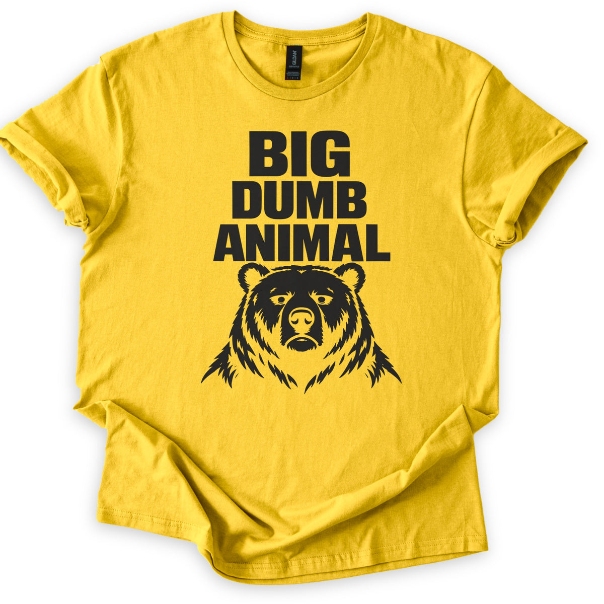 Big Dumb Animal Comfort Colors T-shirt in Daisy, laid flat. Bold black letters read BIG DUMB ANIMAL above a black illustration of a stern, front-facing bear head with shaggy fur. The sleeves are rolled and the shirt lies on a white background.