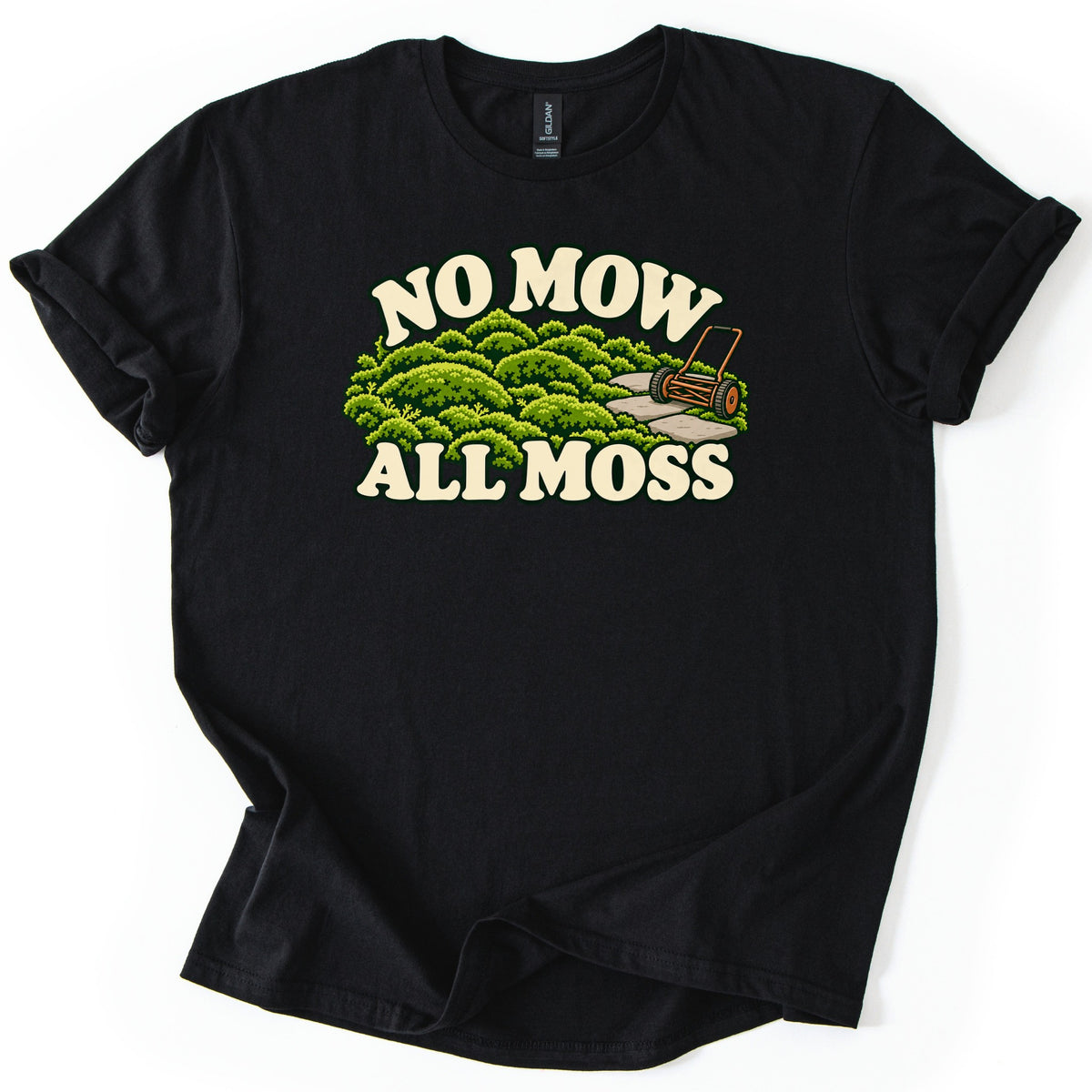 No Mow All Moss Comfort Colors T-shirt in Black, laid flat. Cream retro letters read No Mow above a cartoon of mounded green moss, a stone path and an old push reel mower, with All Moss below. The shirt lies on a white surface with cuffed sleeves.