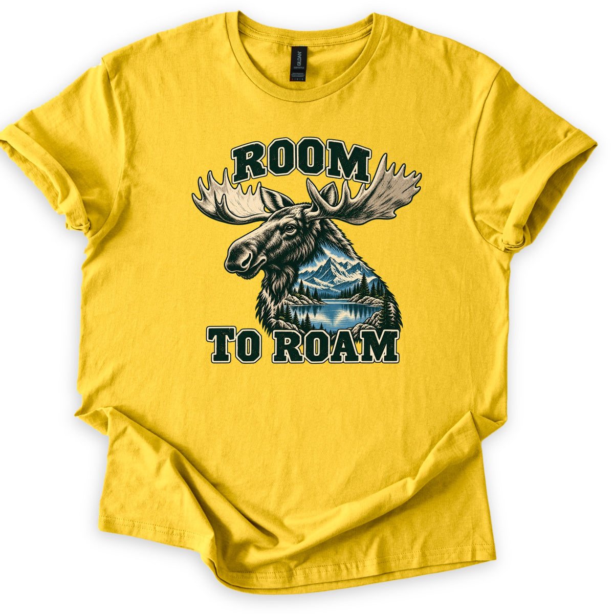 Room to Roam Comfort Colors T-shirt in Daisy, laid flat. A moose head with large pale antlers, its neck filled with a scene of snowy mountains, pine trees and a blue lake, between the words ROOM and TO ROAM in dark green block letters. Sleeves rolled, on a white background.