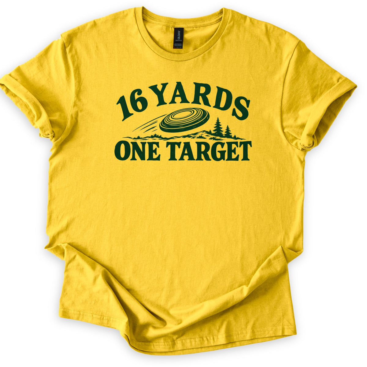 16 Yards One Target Comfort Colors T-shirt in Daisy, laid flat. Dark green print of the words 16 YARDS arched over a speeding clay target, a hilly landscape and pine trees, with ONE TARGET beneath. The shirt lies on a white background with cuffed sleeves.
