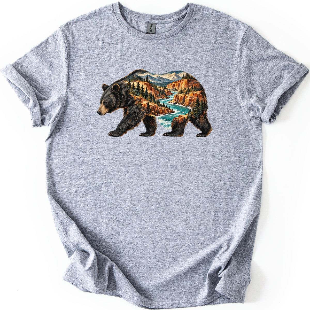 Bear River Canyon Comfort Colors T-shirt in Sport Grey, laid flat. A walking black bear silhouette filled with a canyon scene: a turquoise river winding between orange cliffs, pine trees, and snowy mountains. The heather shirt lies on a white background with sleeves rolled.